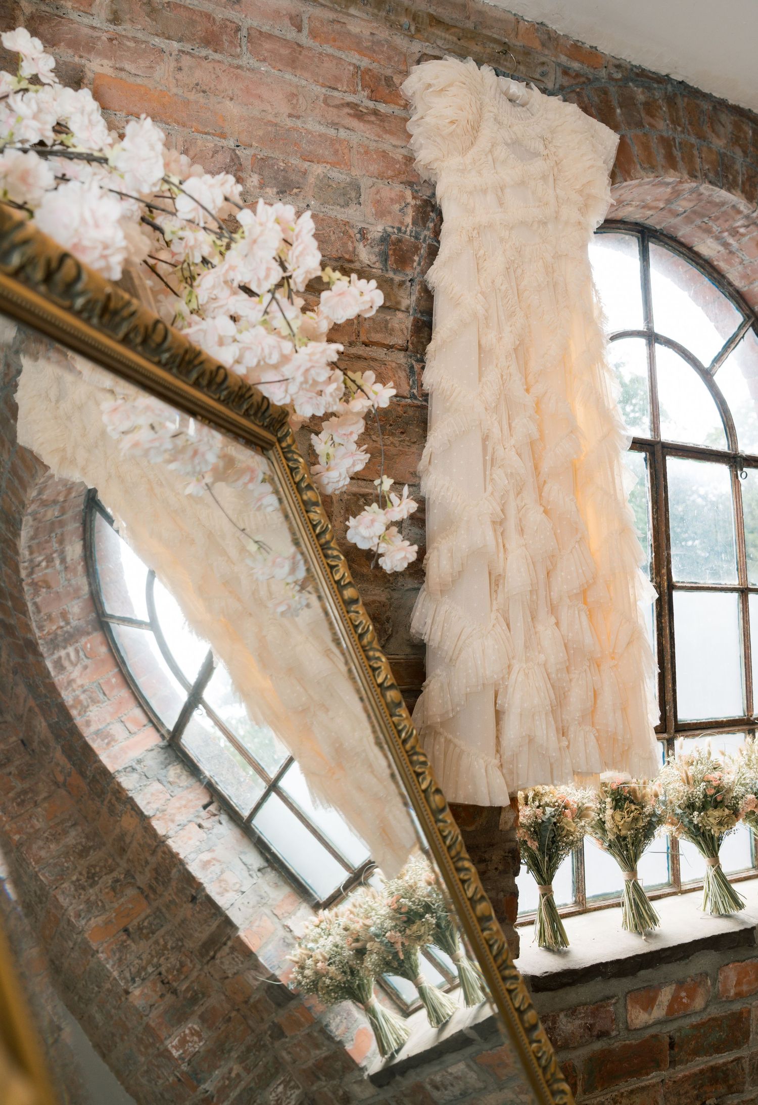 Ornate window arch with exposed brick and cascading white floral arrangements creating a romantic ambiance.