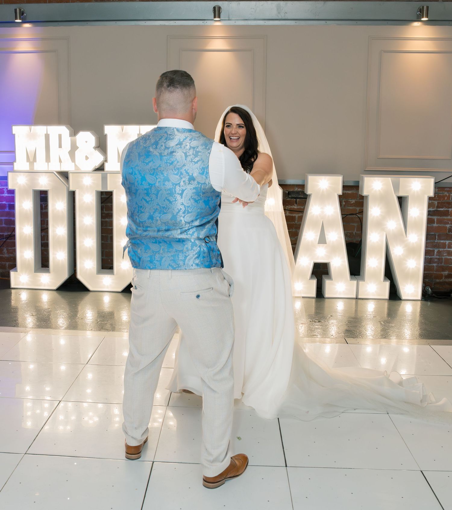 Illuminated 'MR & MRS' marquee letters create a romantic backdrop at the wedding reception.