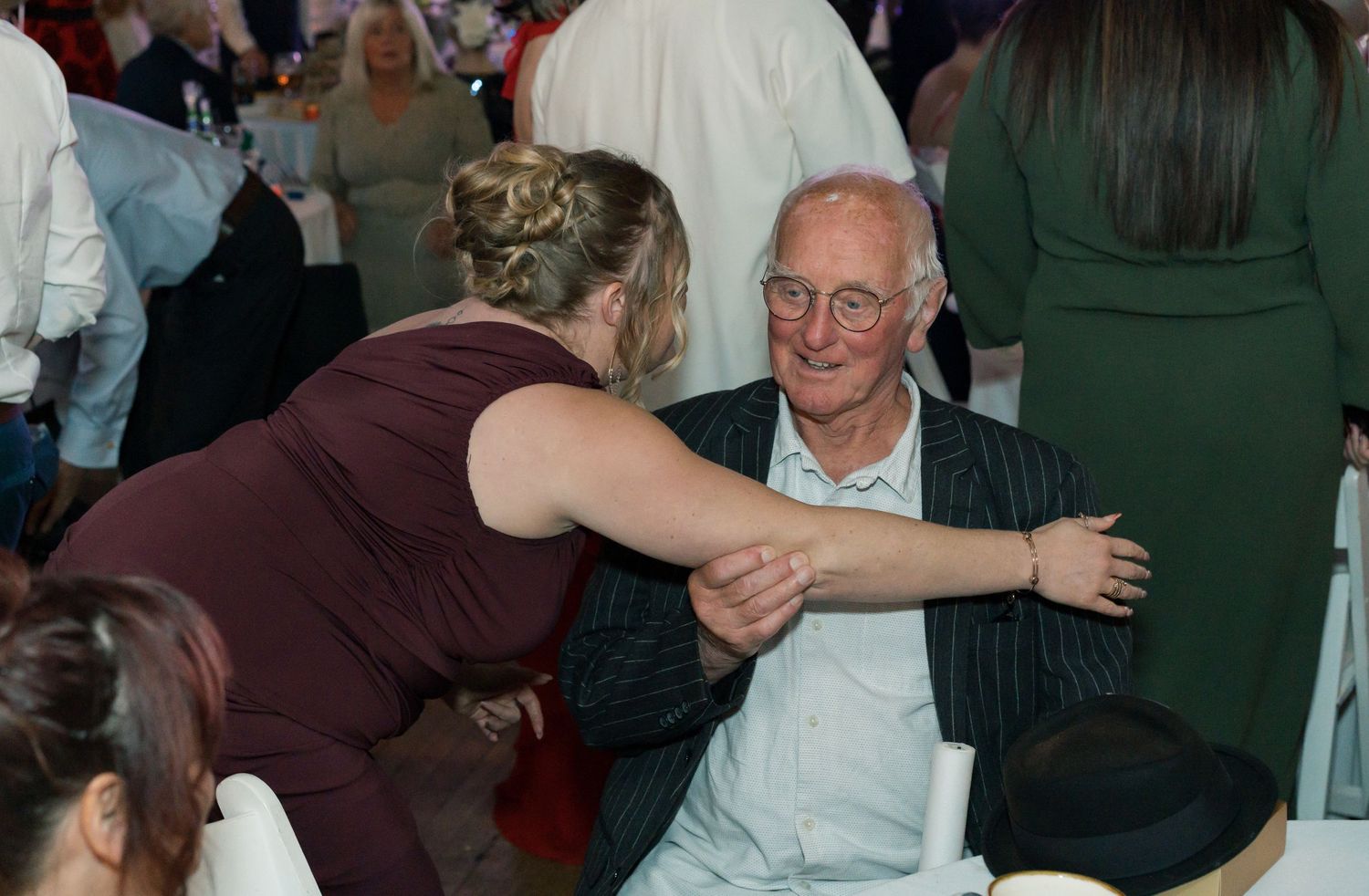 Wedding reception guests dancing and celebrating in an indoor venue.
