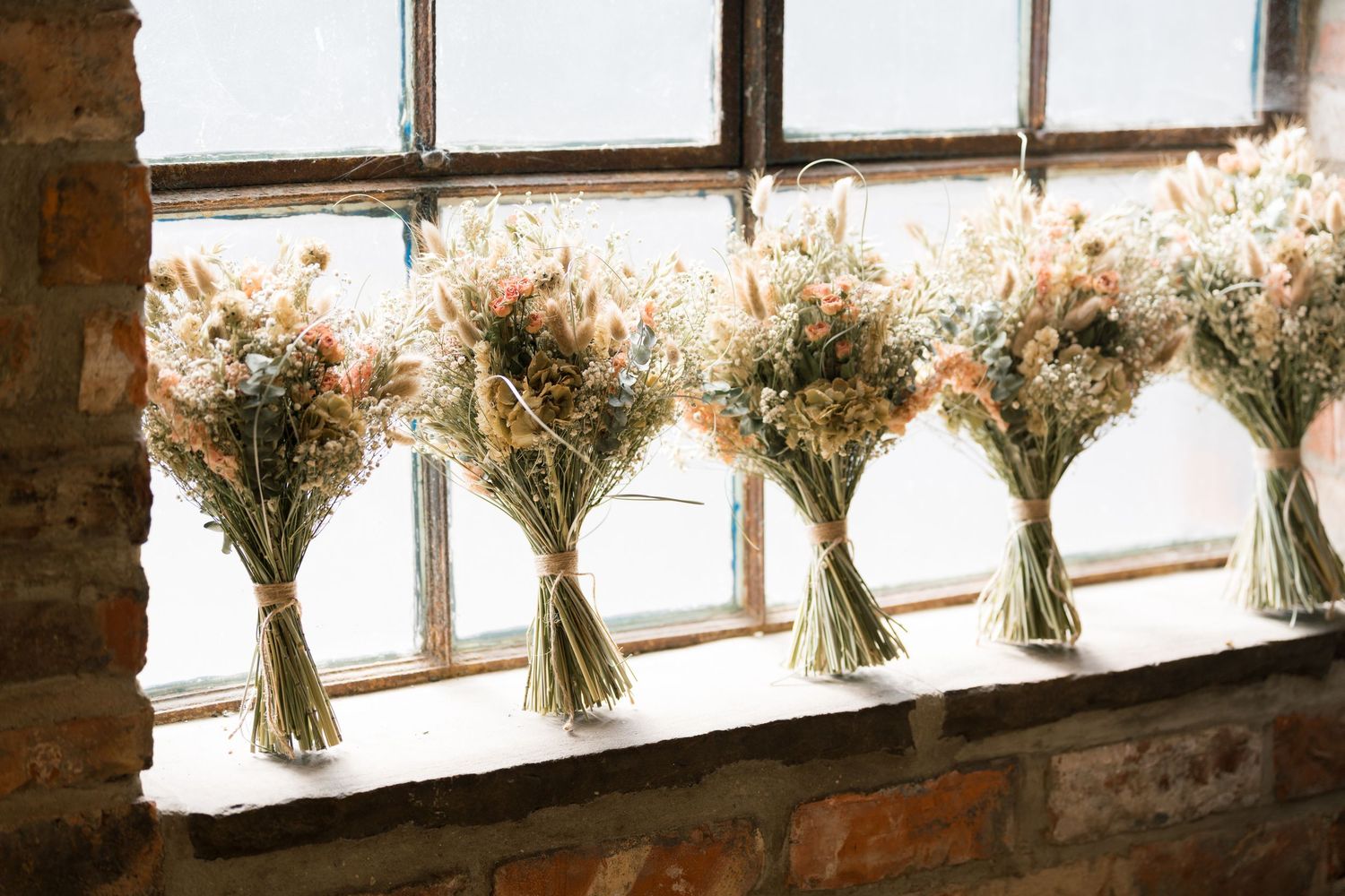 Dried flower bouquets line a rustic windowsill in an industrial brick venue.