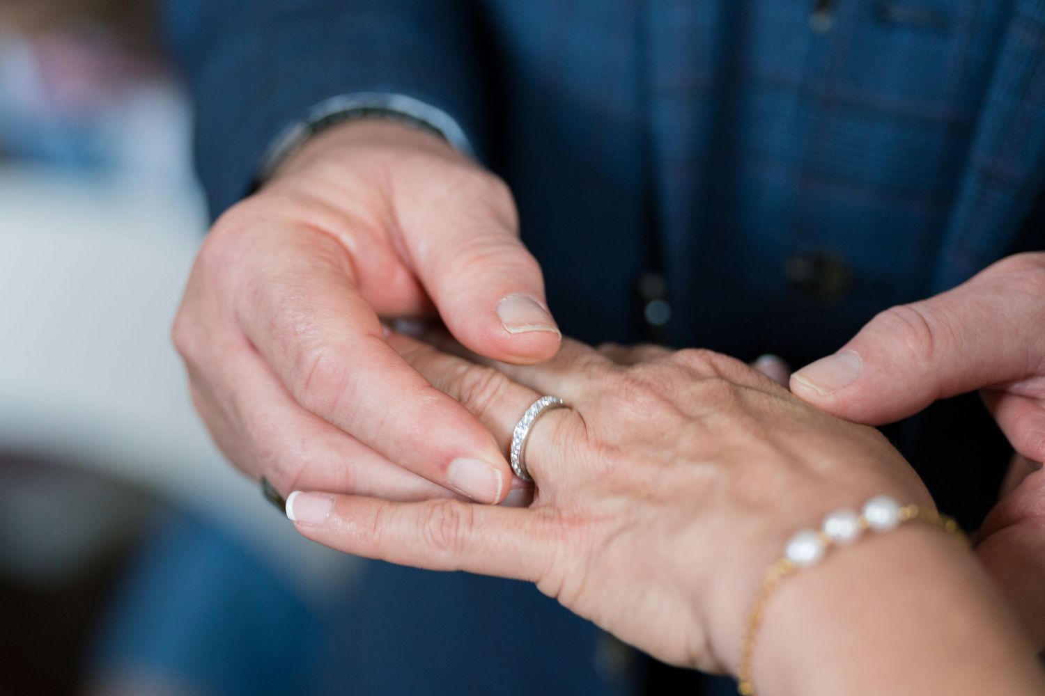 Close-up of hands exchanging wedding rings during ceremony.