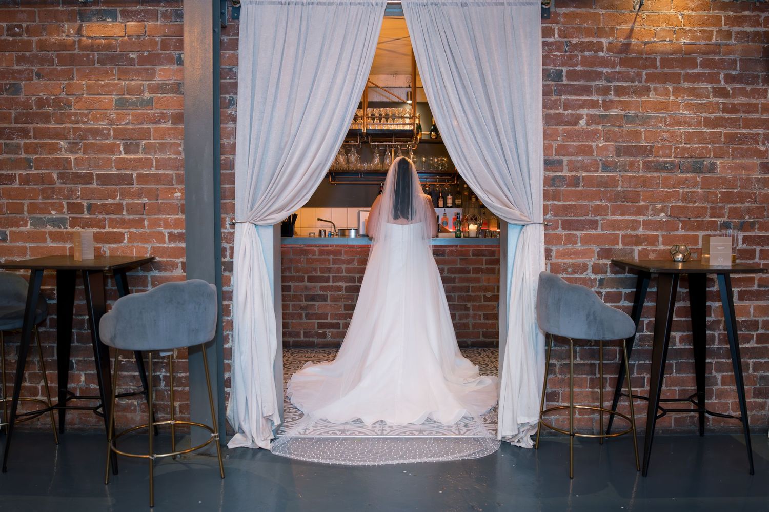 White sheer curtains create an elegant backdrop against exposed brick walls in an industrial-style venue space.