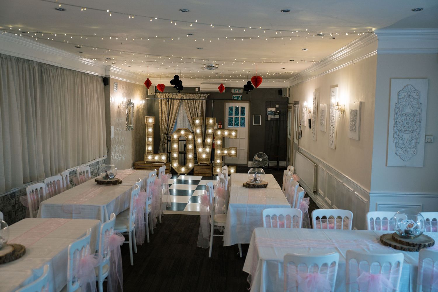 Elegant wedding reception venue with white chairs and sparkling ceiling lights.