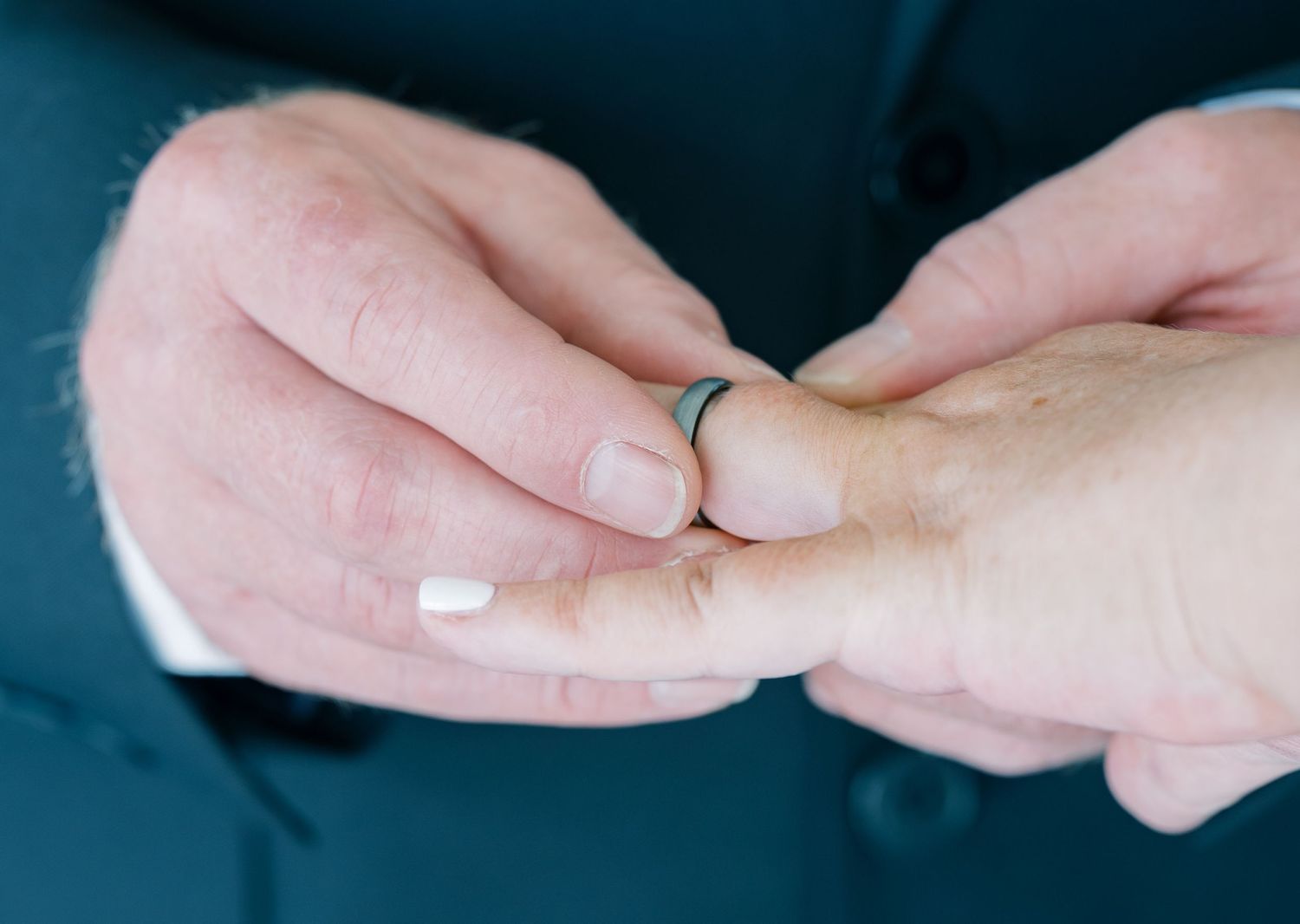 Close-up shot of hands exchanging wedding rings during the ceremony.