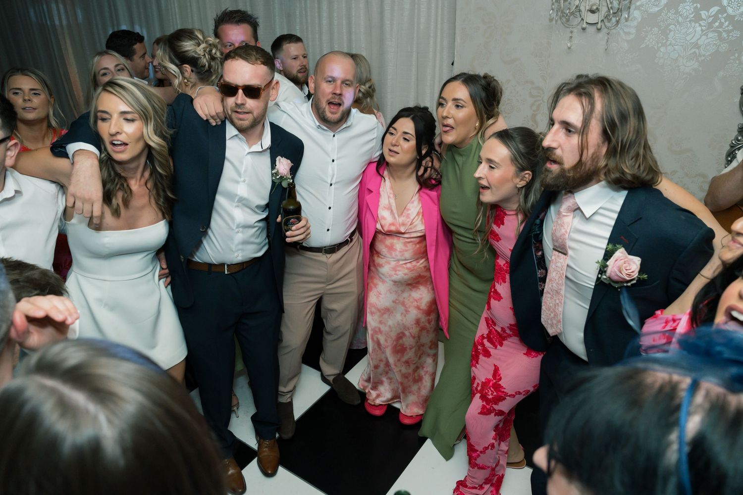 Wedding reception dance floor filled with guests celebrating and dancing.