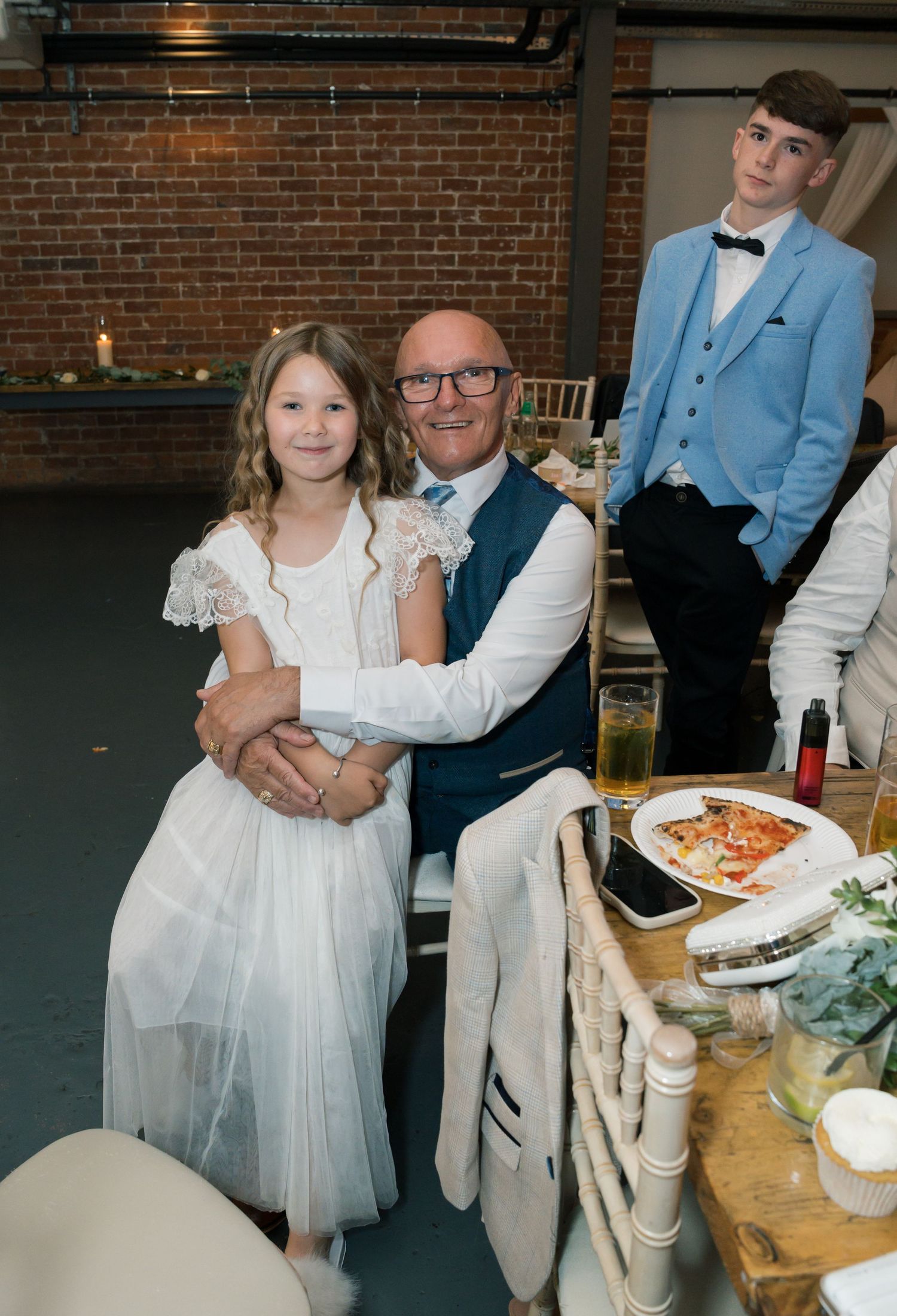 Wedding reception gathering with formal attire and rustic decor at indoor venue.