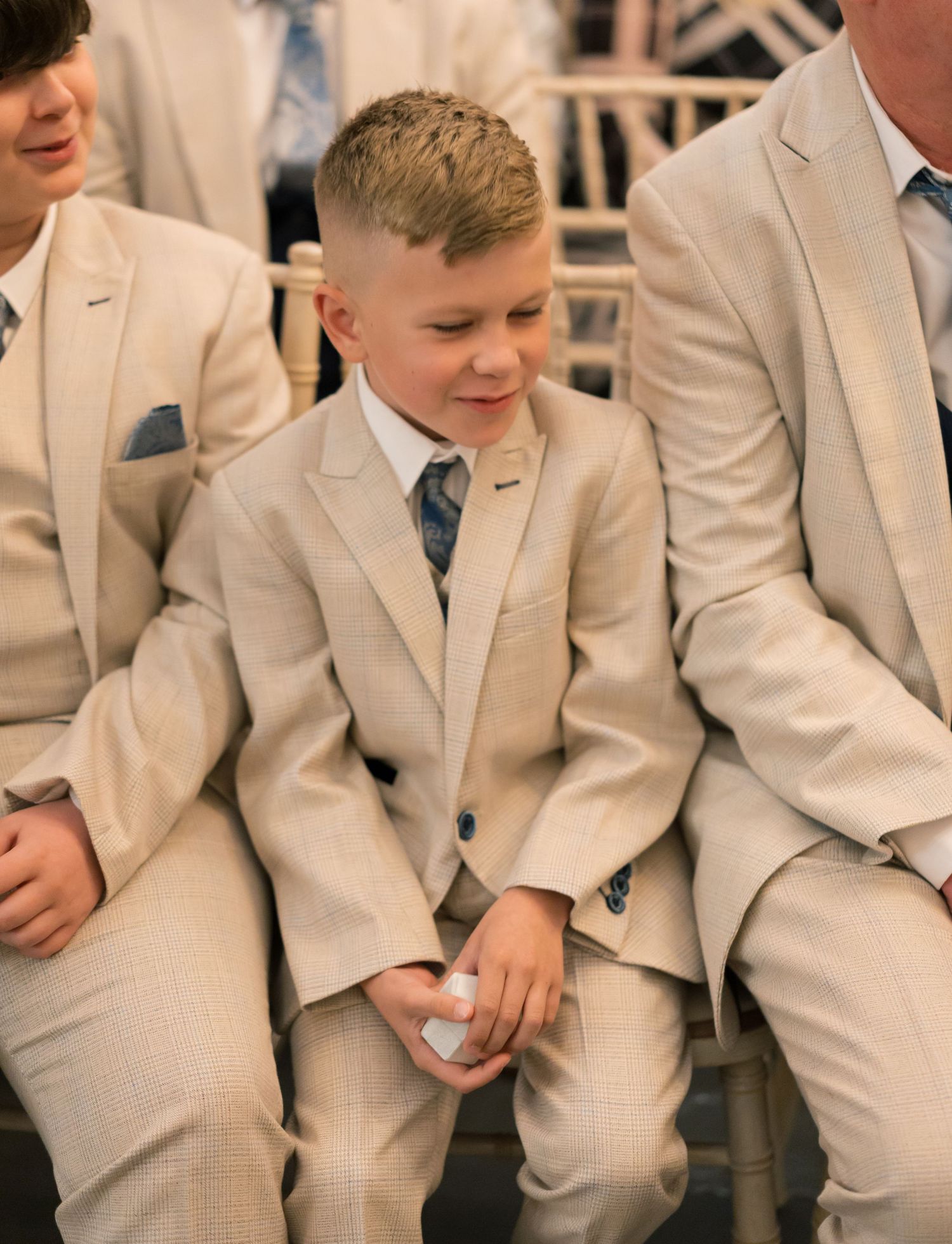 Groomsmen wearing matching beige suits with blue ties at a wedding celebration.