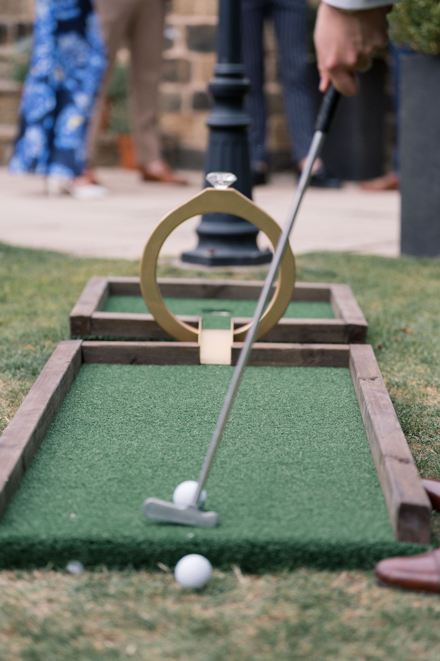 Close-up sequence of a miniature golf putt rolling through a curved obstacle course on artificial turf.