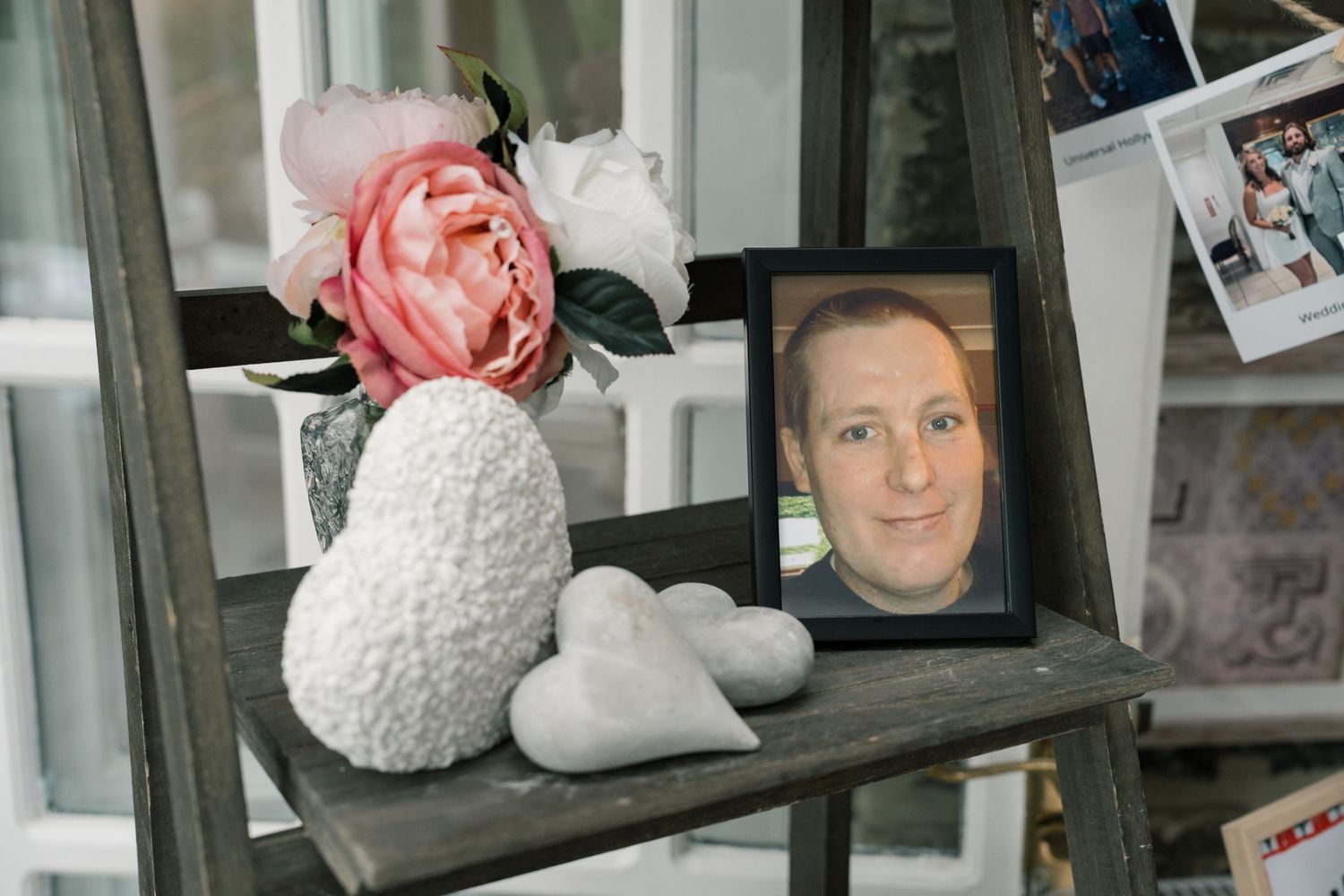 Decorative display shelf with white ceramic items and framed photographs arranged in a rustic style.