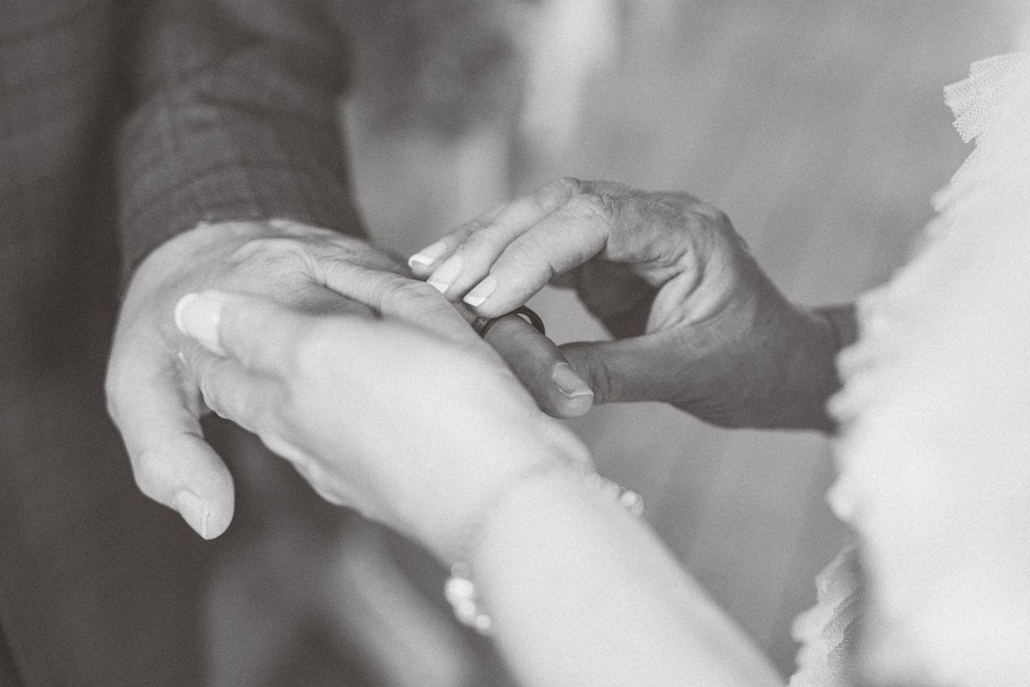 Close-up black and white photo sequence showing a hand tearing a piece of paper into smaller pieces.