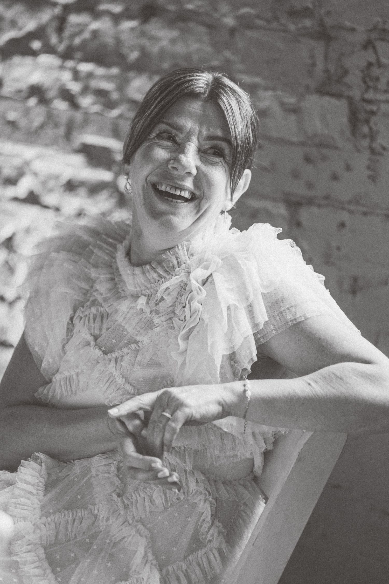 Black and white portraits show a bride in a ruffled white dress laughing joyfully.