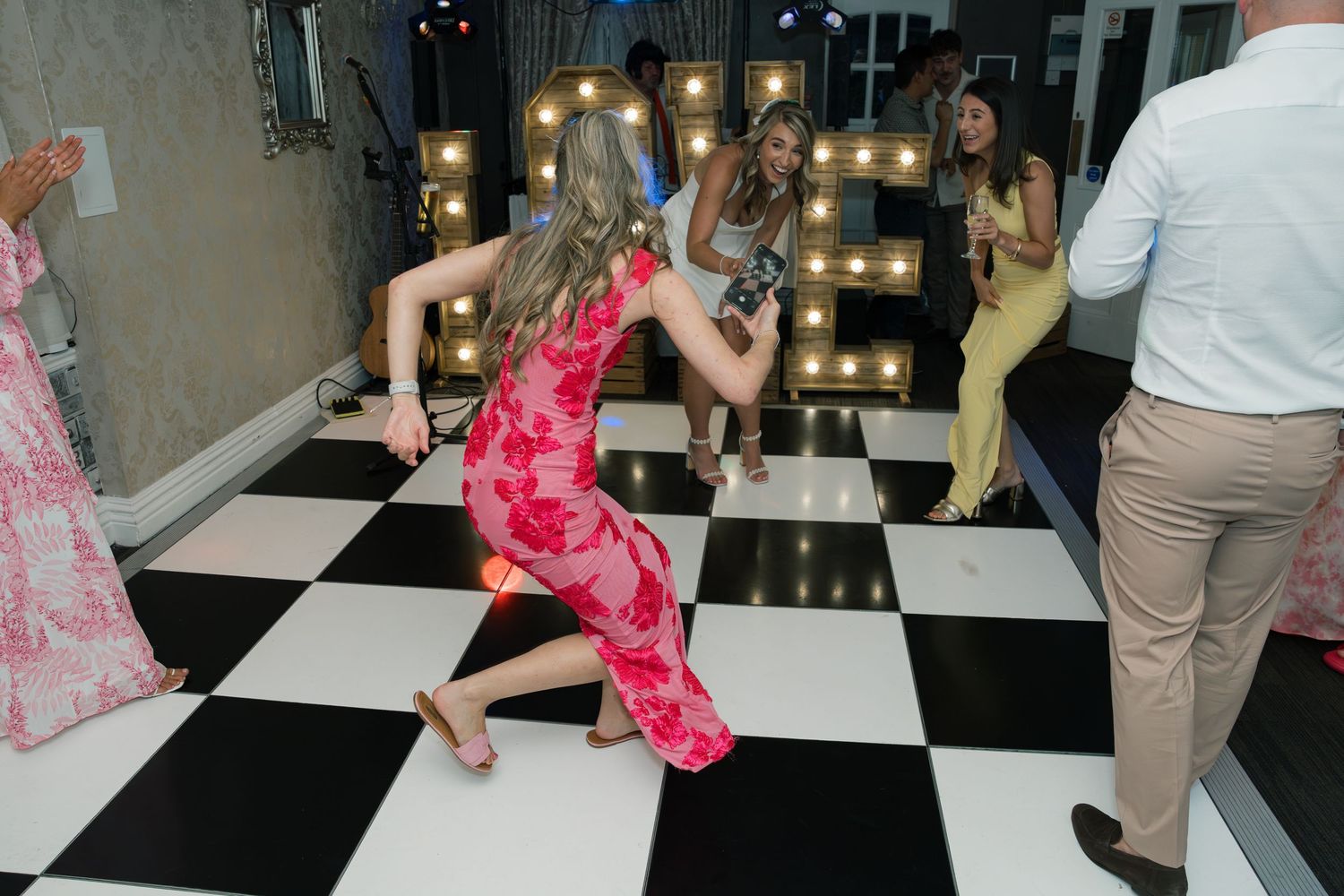 Party guests dancing on black and white checkered dance floor.
