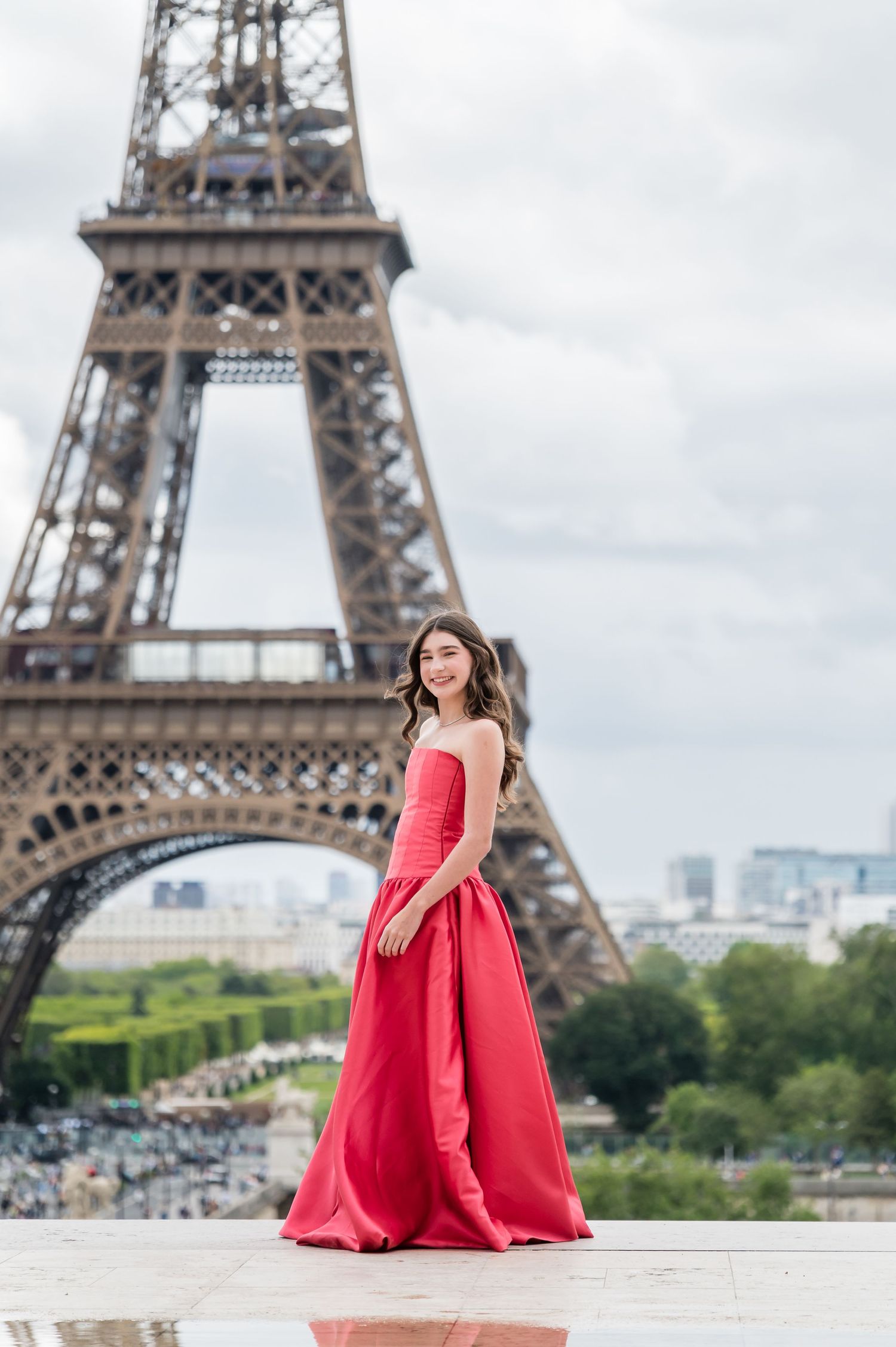 A flowing red ballgown evening dress shown in a series of photos with the iconic Eiffel Tower landmark in Paris as backdrop.