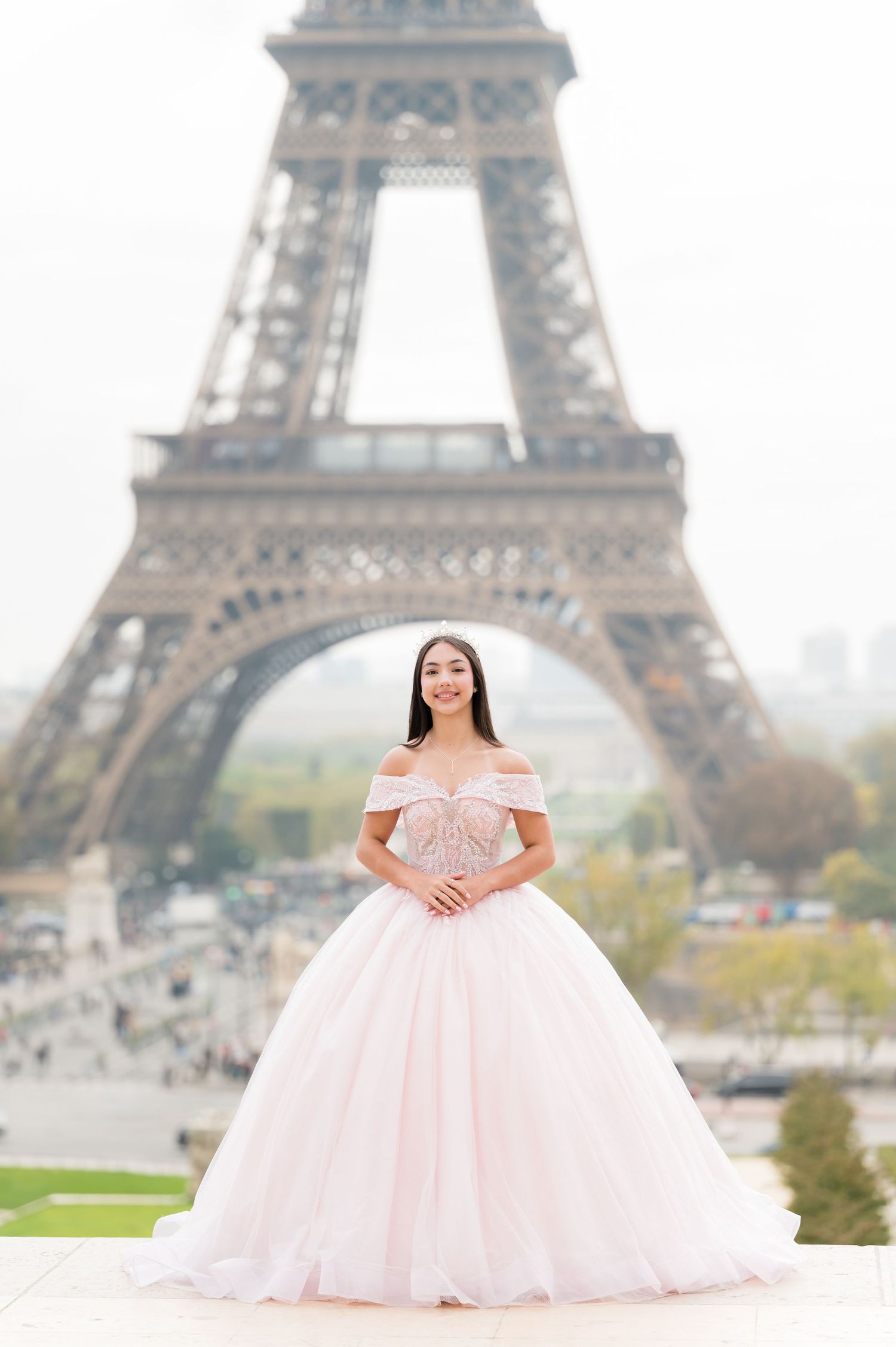 A stunning pink ballgown dress photographed in front of the iconic Eiffel Tower in Paris on a misty day.