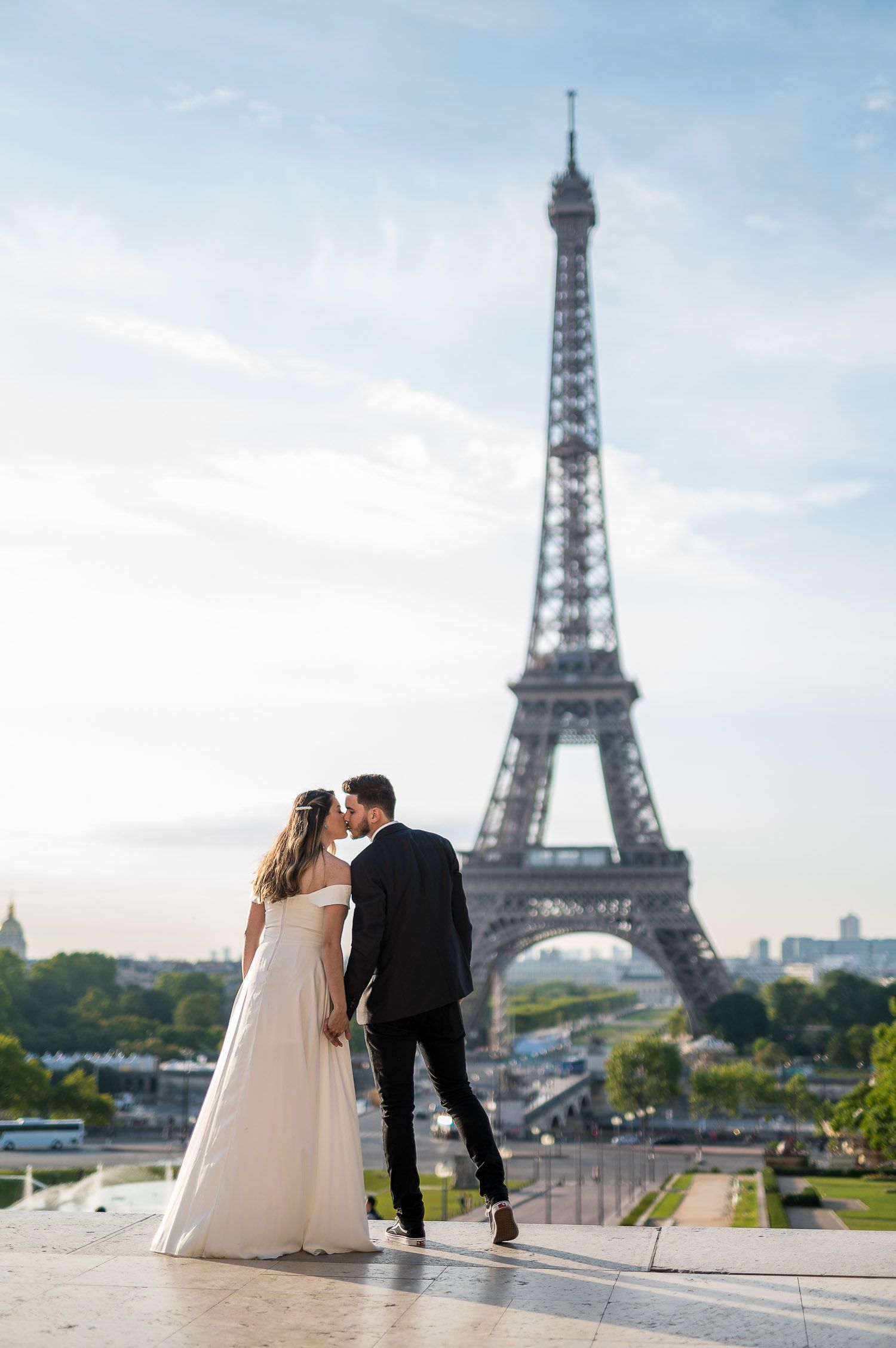 A romantic wedding couple embracing with the iconic Eiffel Tower in Paris as their stunning backdrop.