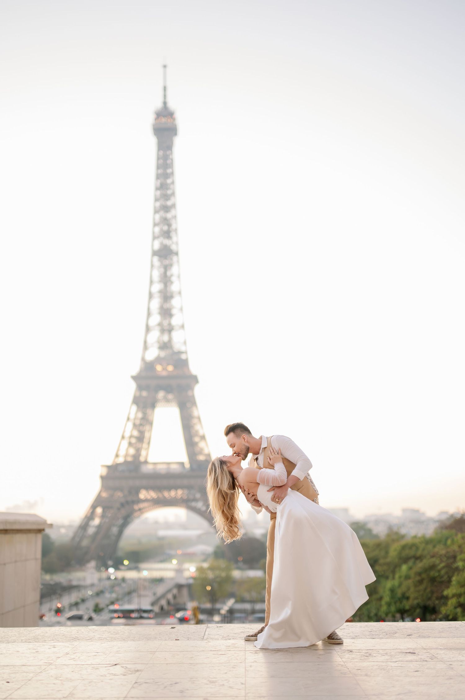 Couple sharing a romantic dip kiss in front of the Eiffel Tower in Paris at golden hour.