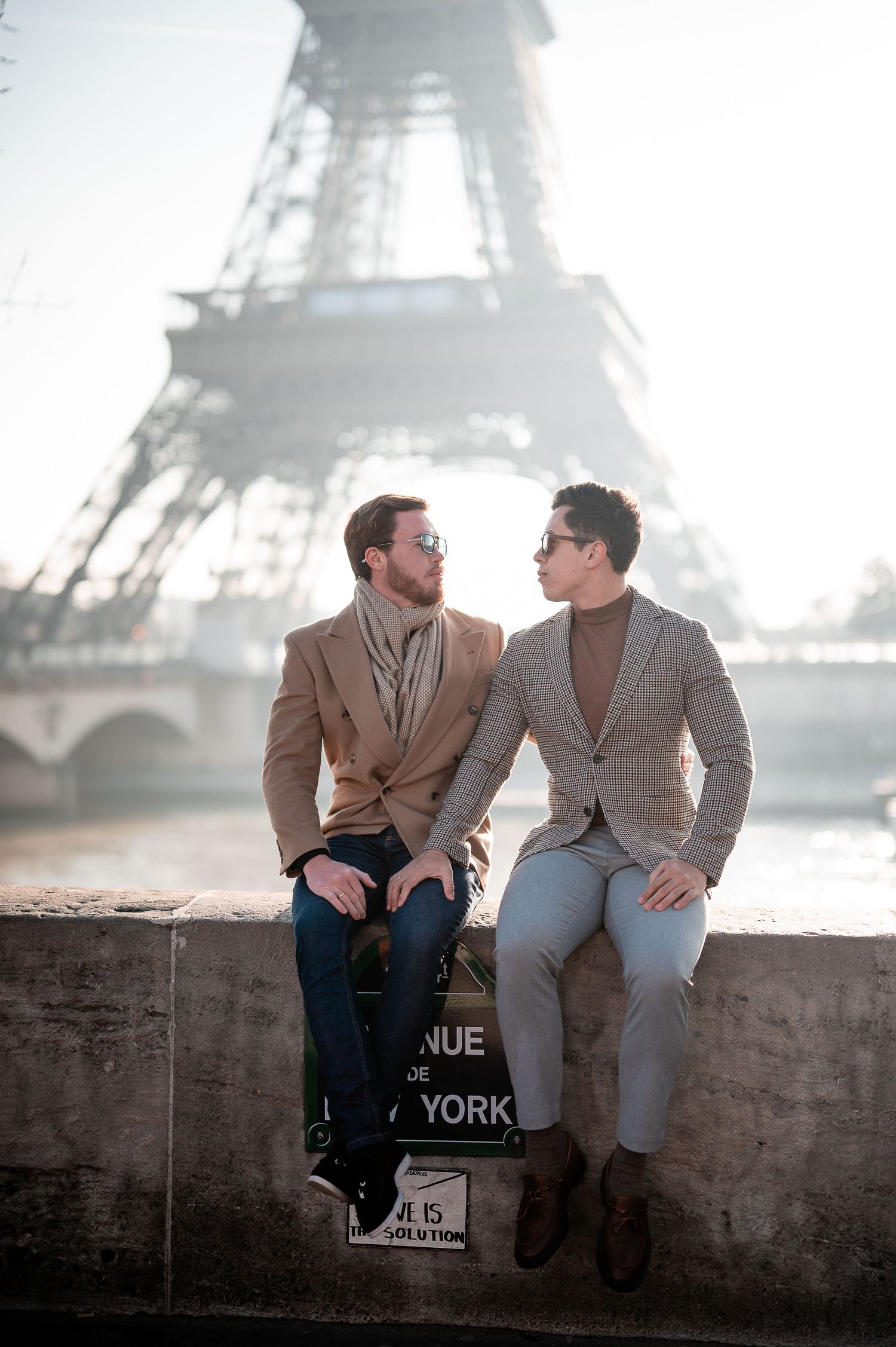 Two people share an intimate moment on a wall near the Eiffel Tower in Paris.