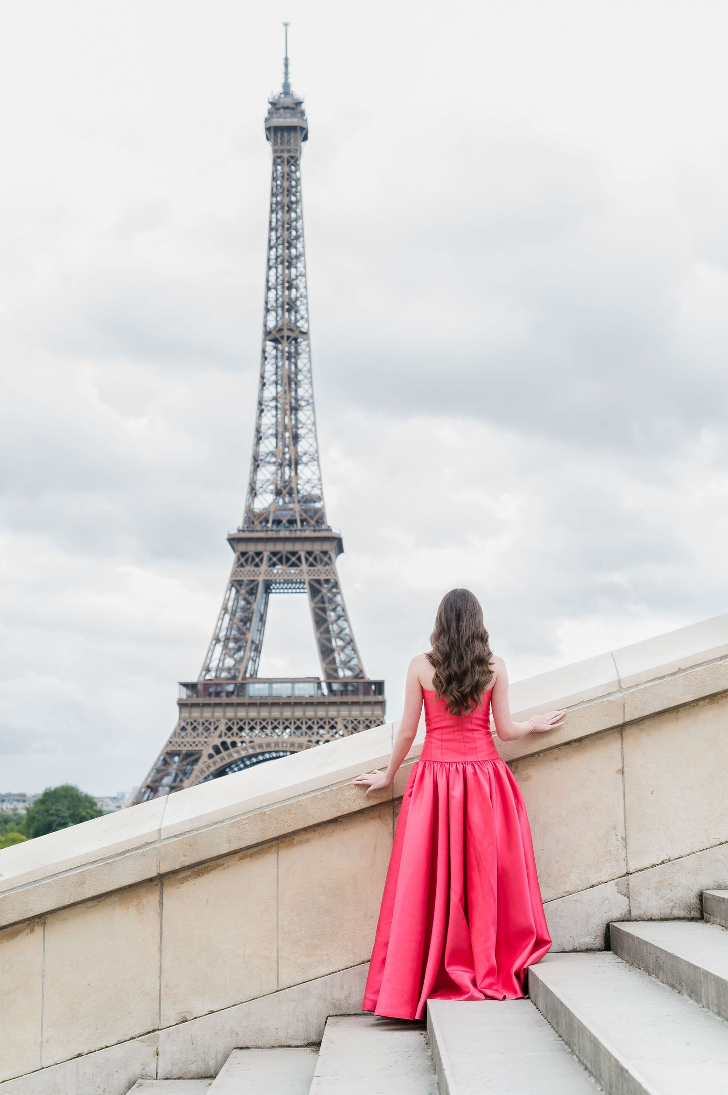 A sequence of images showing a person in a flowing pink dress posing with the Eiffel Tower in Paris.