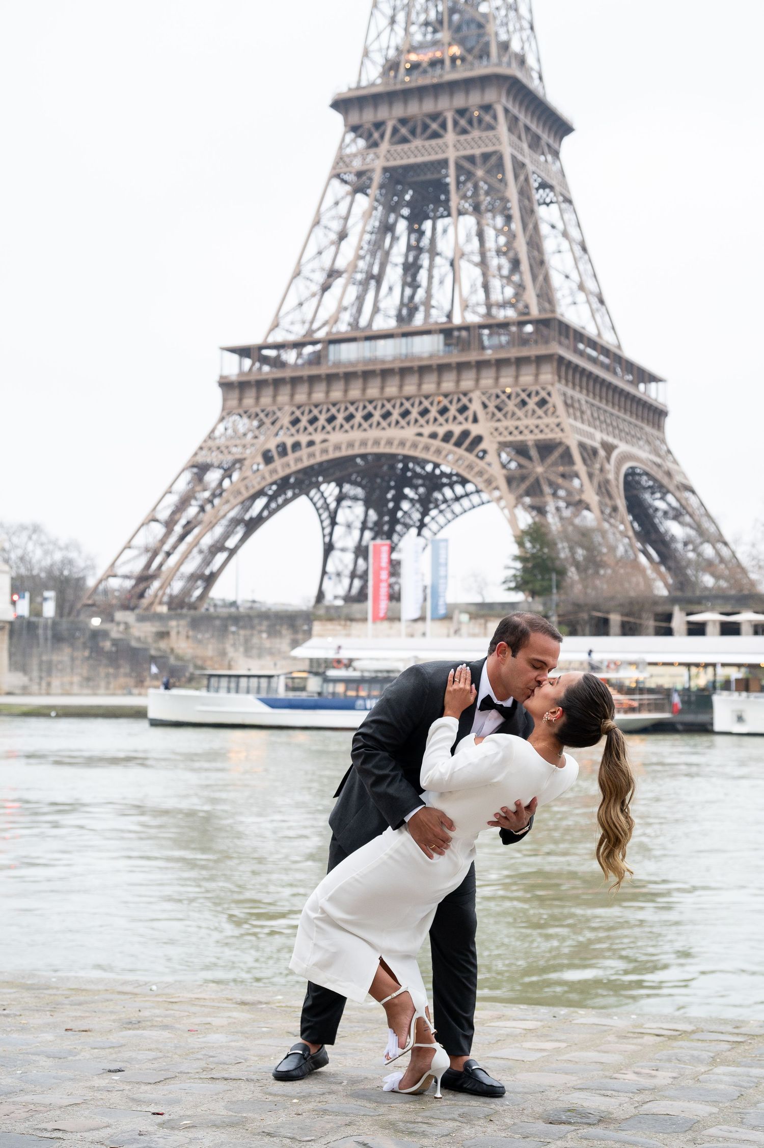A romantic dip pose captured in front of the Eiffel Tower with the Seine River in the background.