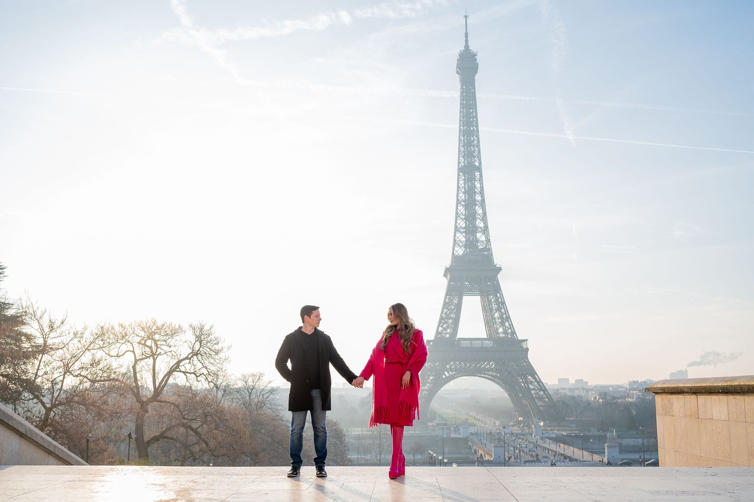 Silhouettes holding hands against winter sky with Eiffel Tower in background.