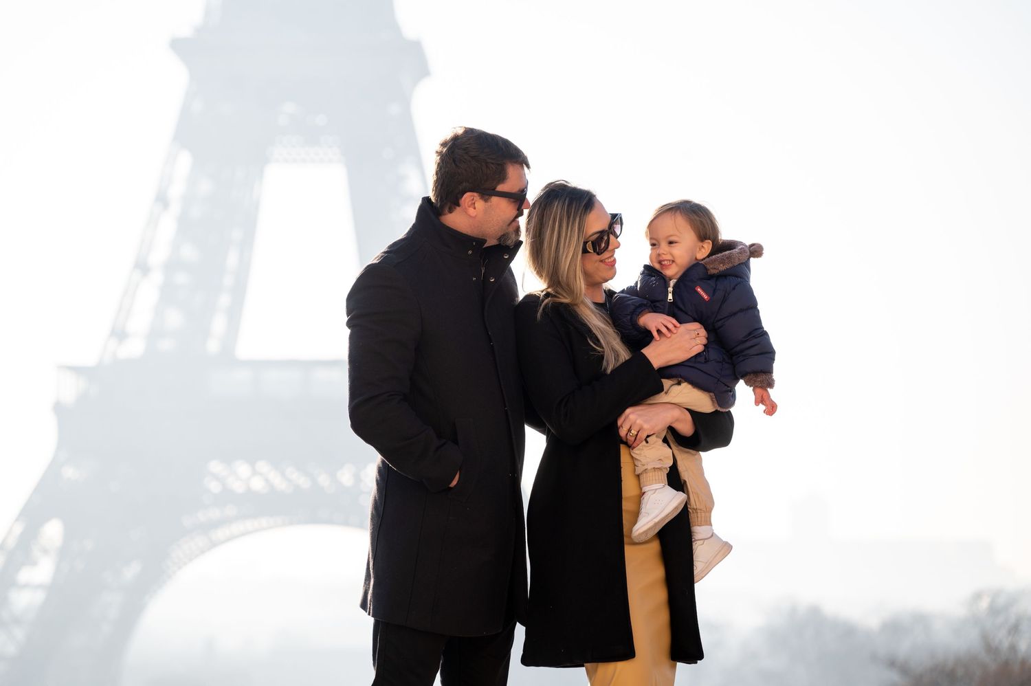 Family photo shoot against misty Eiffel Tower backdrop in Paris.