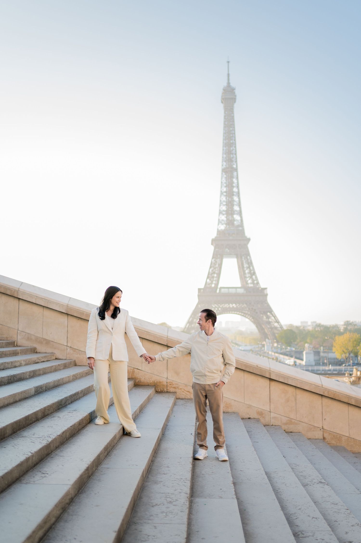 Three photos show people in white outfits posing on stone steps with the iconic Eiffel Tower visible in Paris.