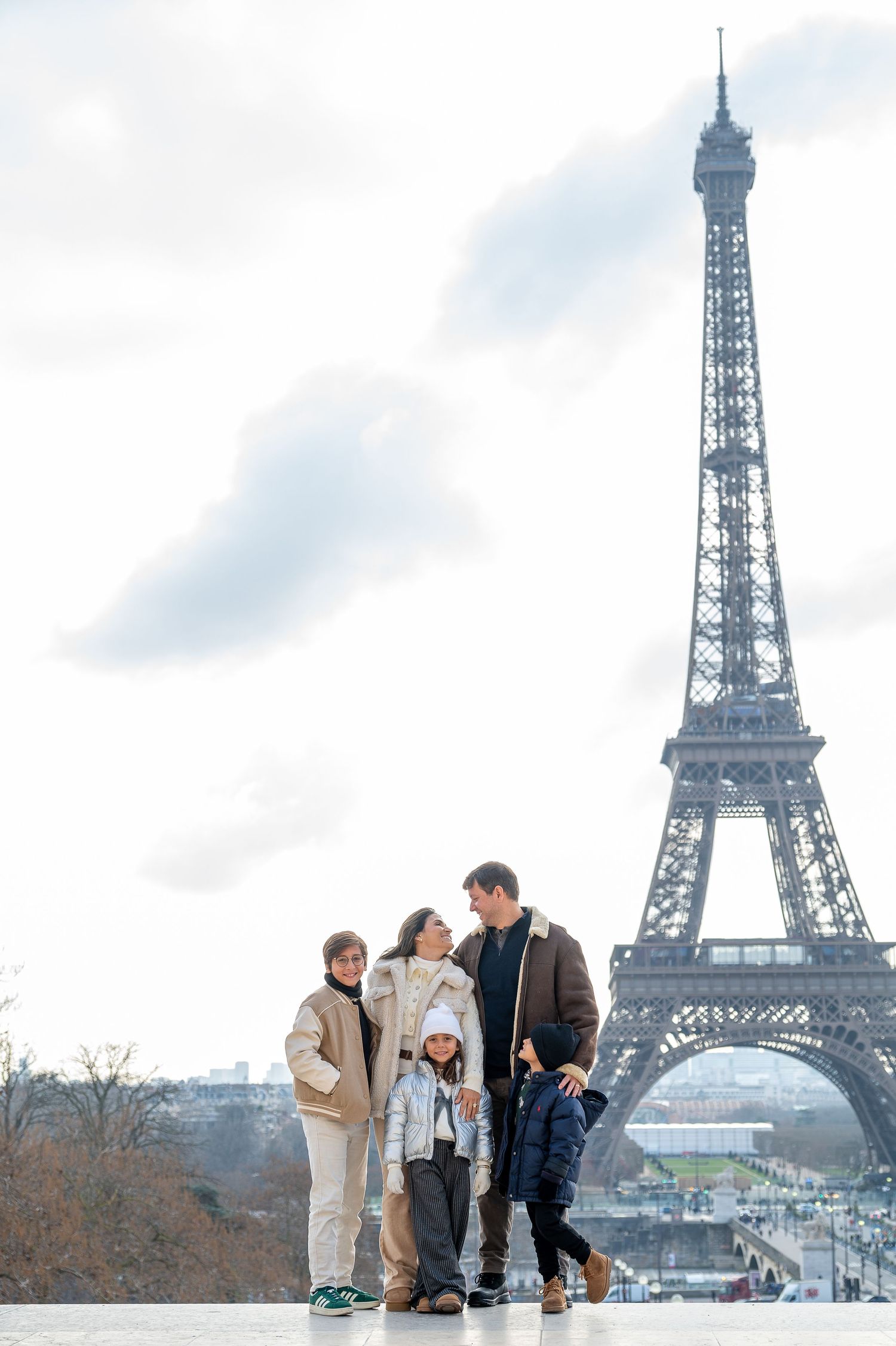 A winter scene in Paris with a group standing together against the cloudy backdrop of the Eiffel Tower.