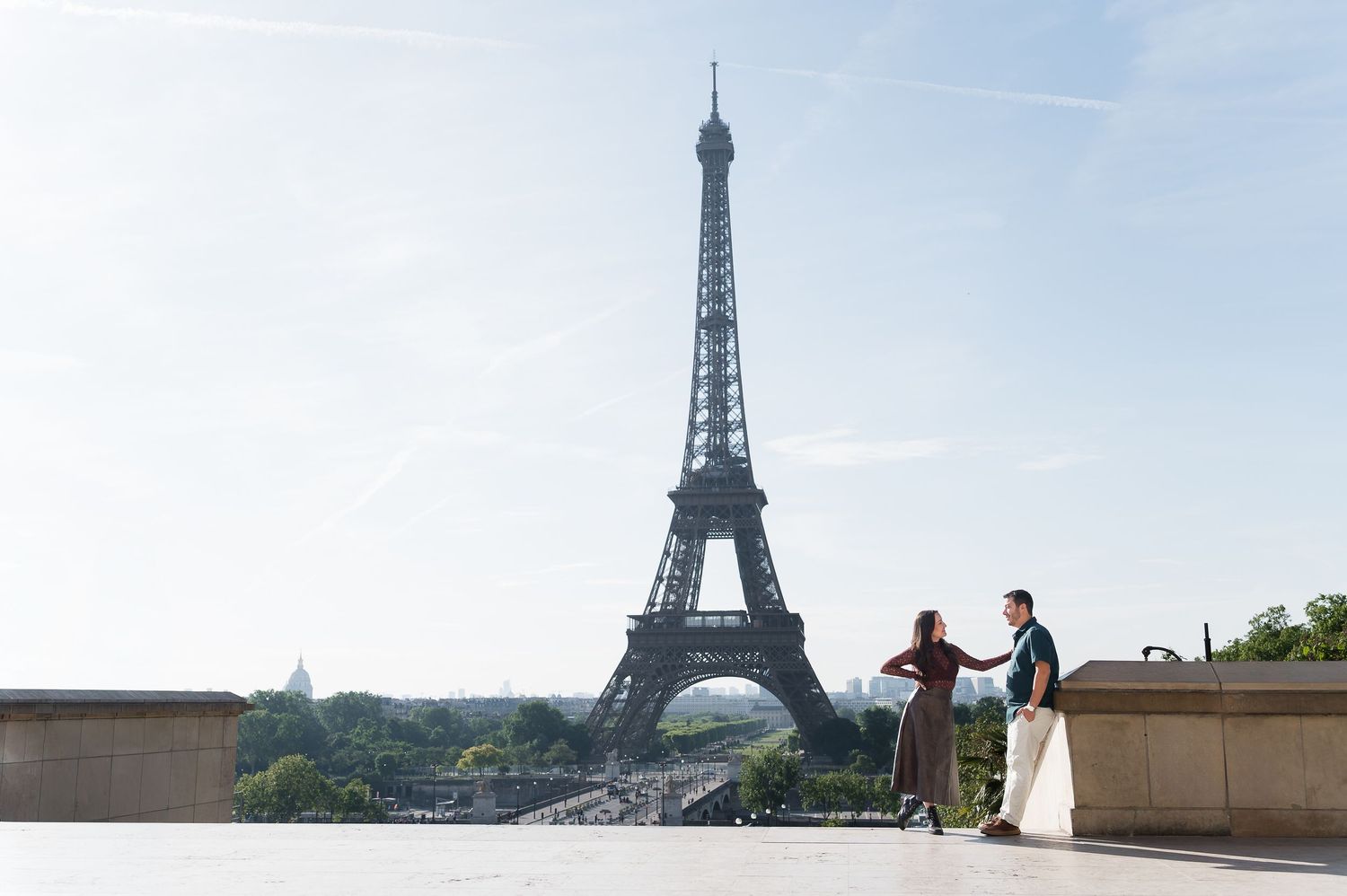 Couple dancing romantically in front of the Eiffel Tower in Paris on a sunny day.