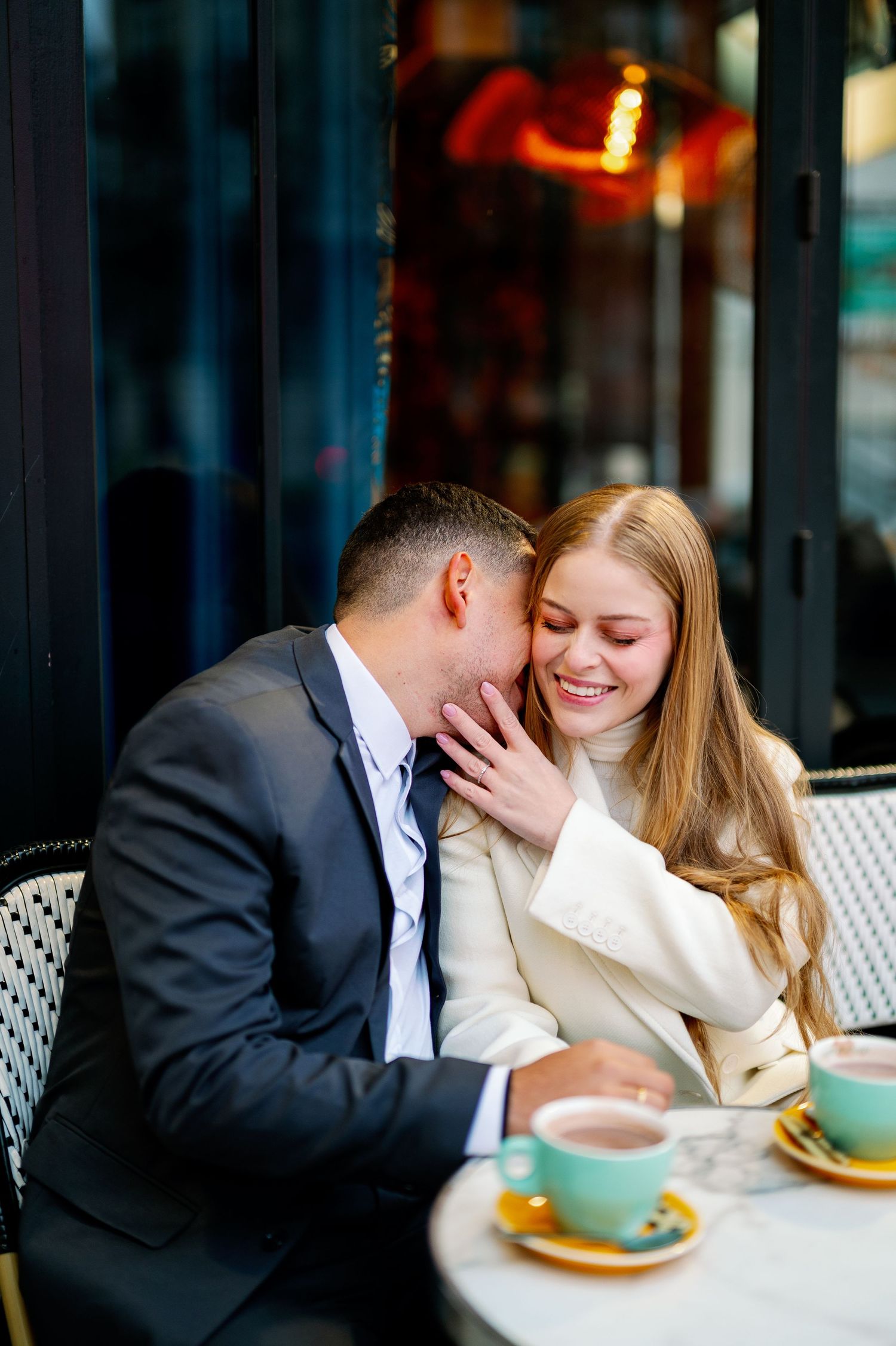 Intimate moment at a Parisian cafe with coffee cups and warm lighting.
