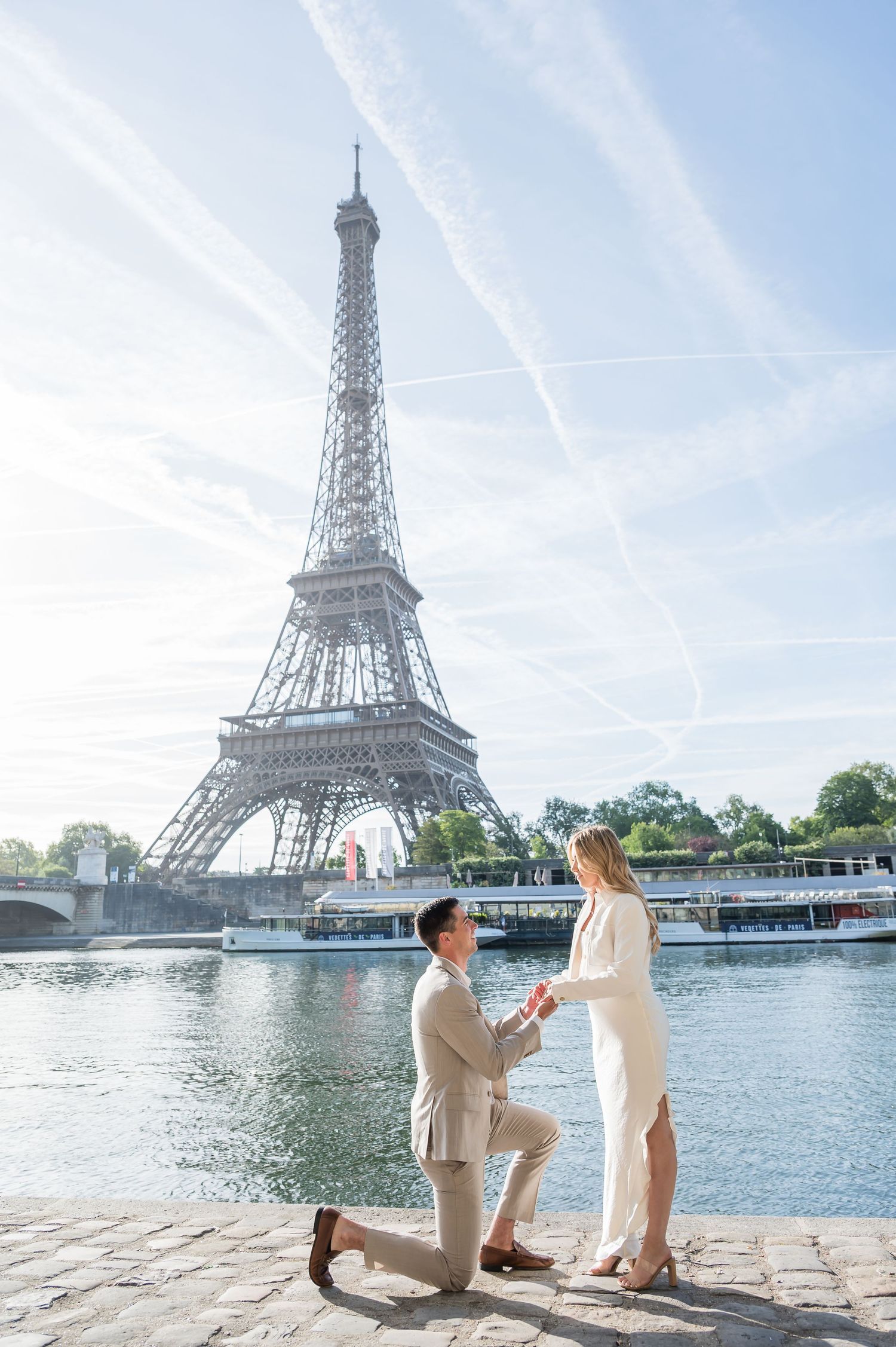A proposal scene with the iconic Eiffel Tower in Paris with boats on the Seine river in the background.