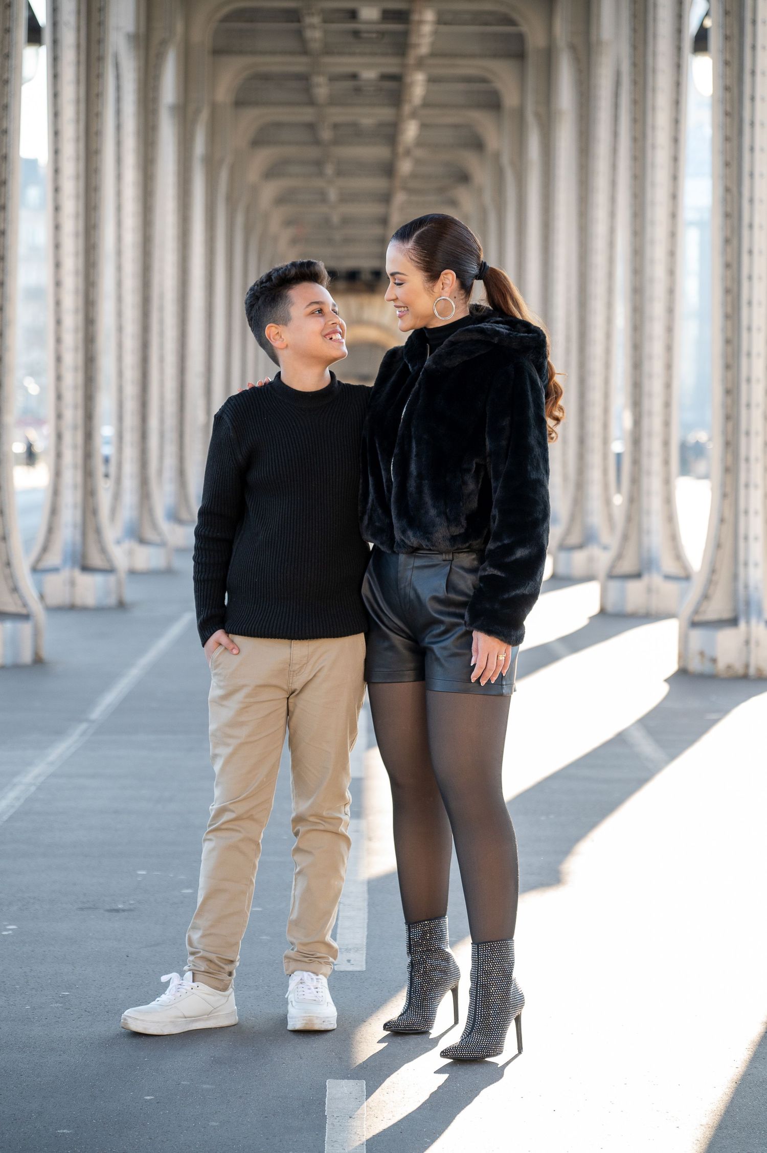 Couple standing in archway corridor with repeating architectural columns in Paris.