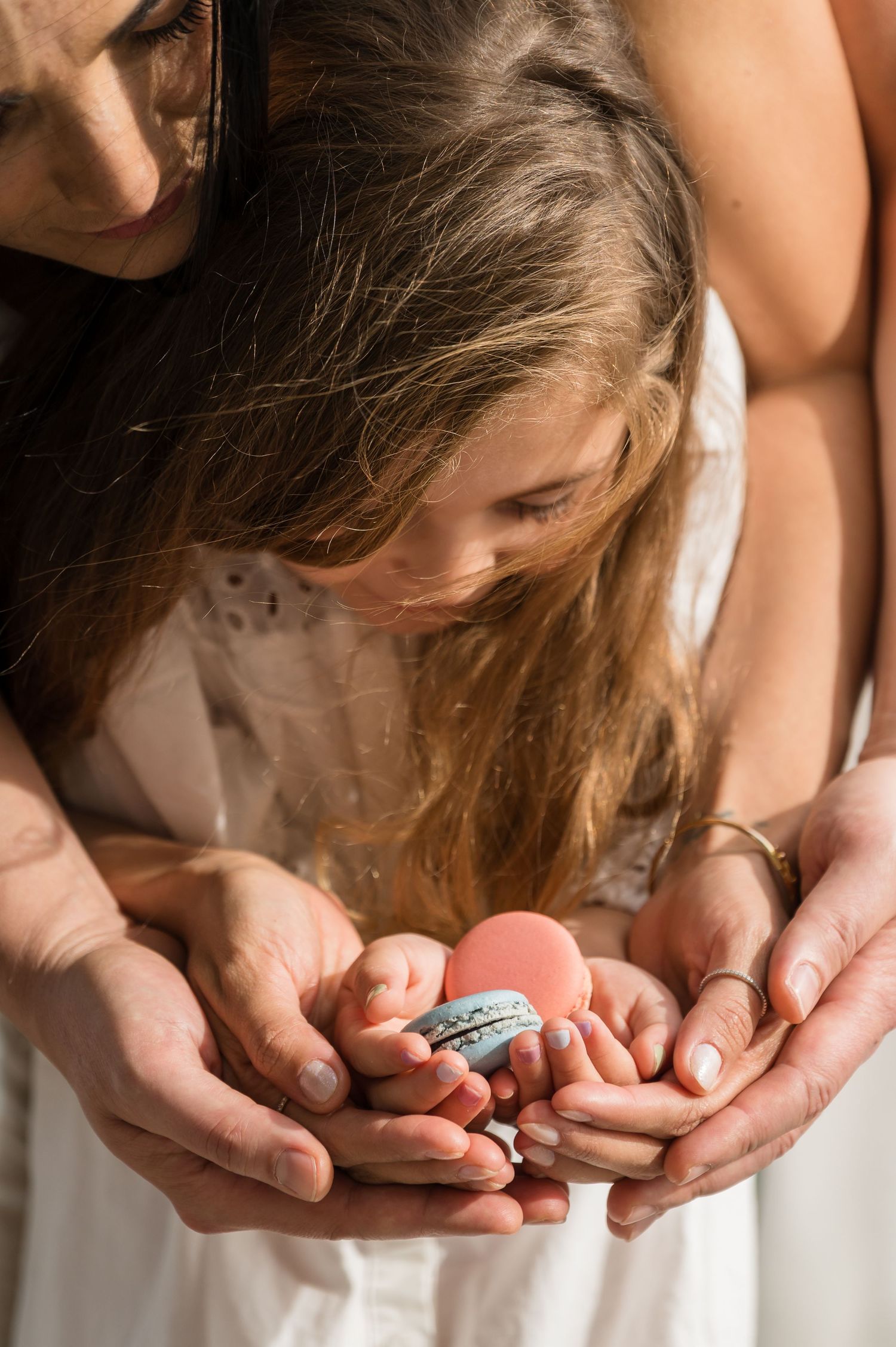 Hands gently cupping and examining a small pink egg against a light background.