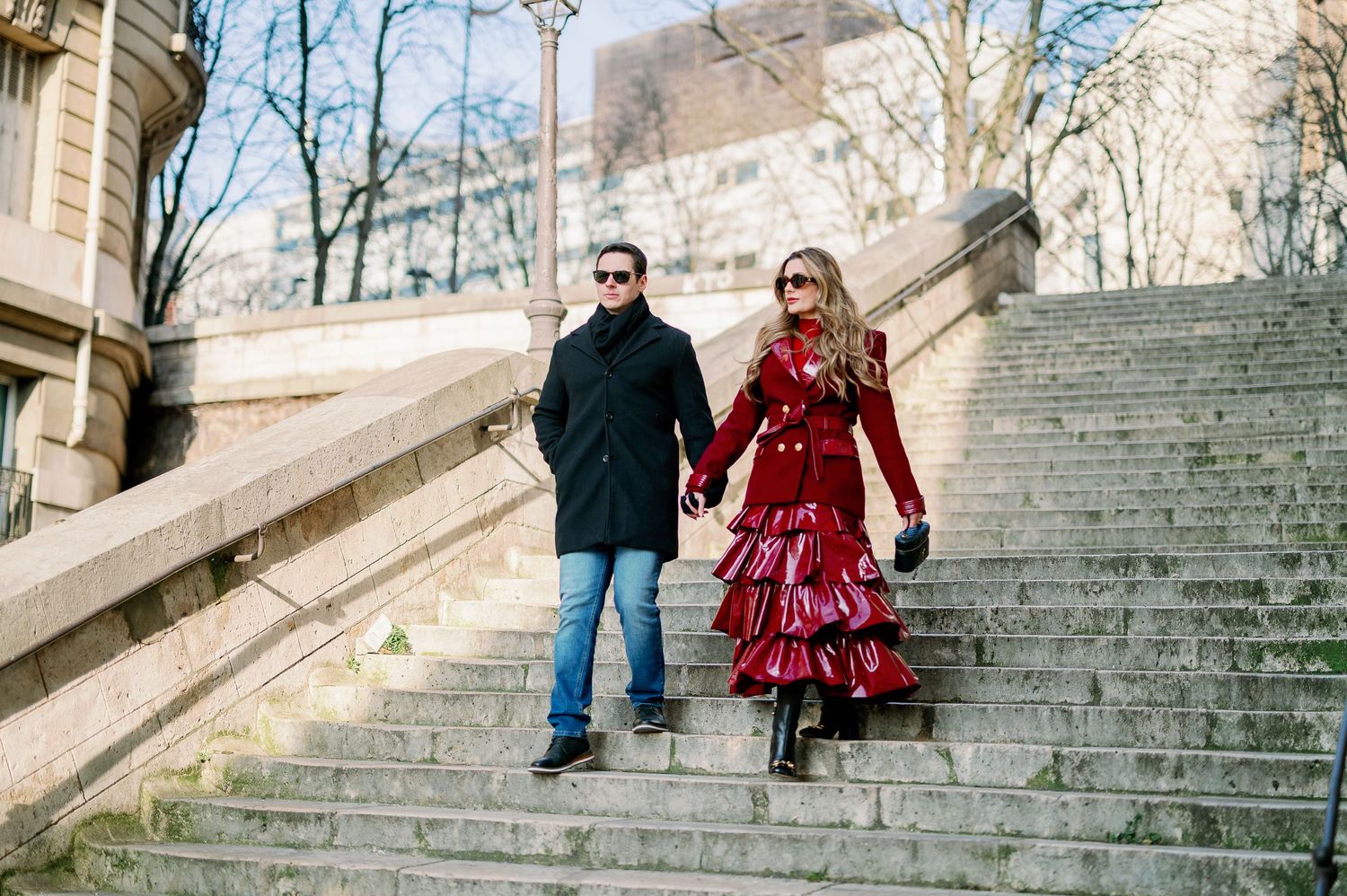 Couple descending stone steps in Paris wearing stylish winter outfits.