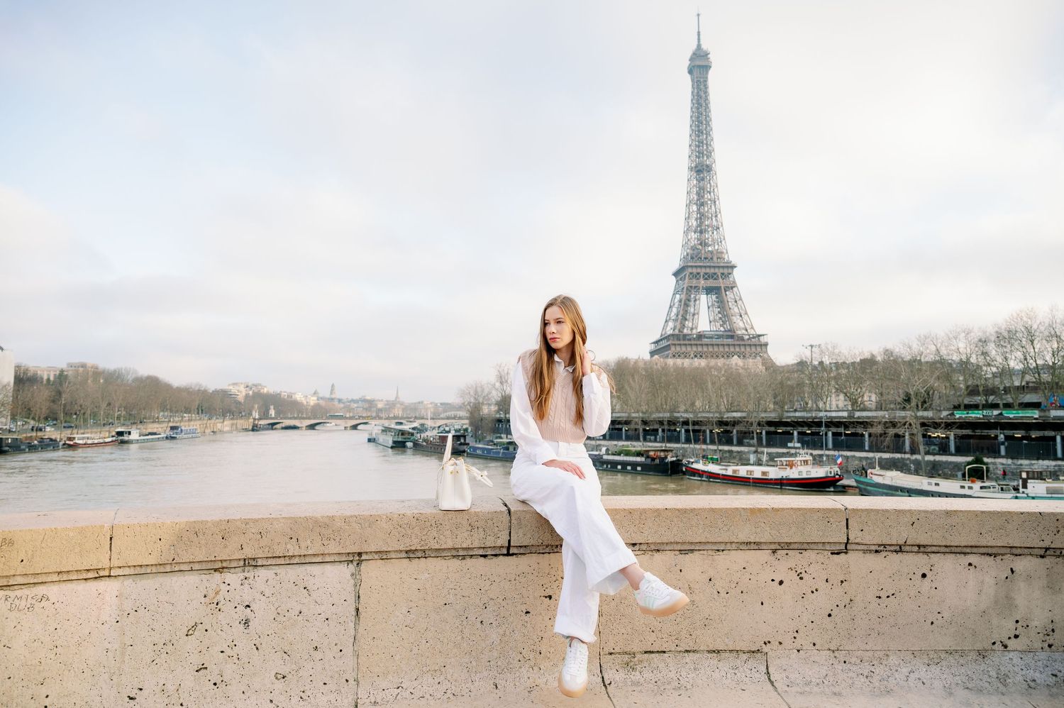 Playful fashion pose with the Eiffel Tower and Seine River in the background.