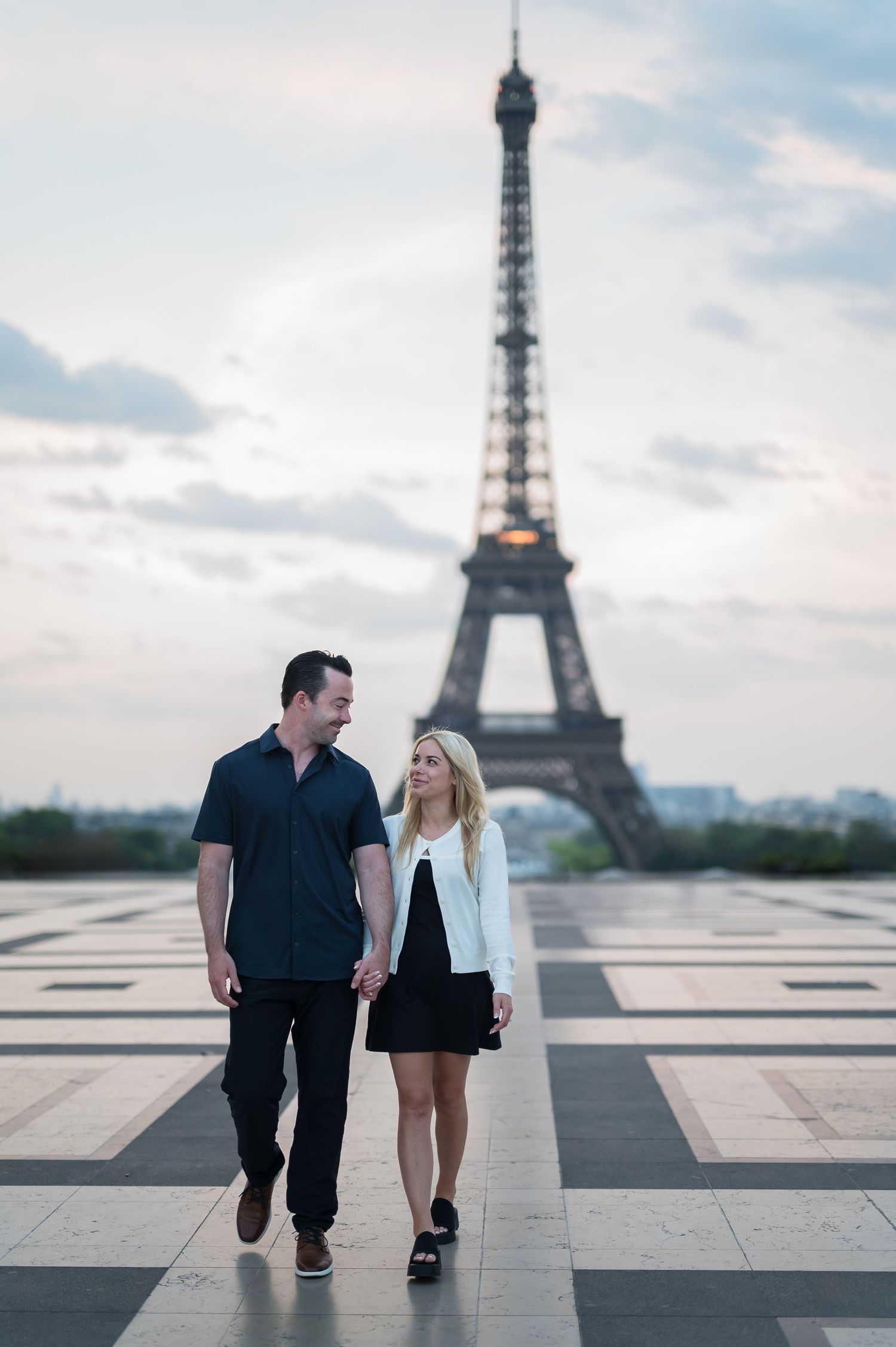 A couple walks together at Trocadero plaza with the iconic Eiffel Tower rising majestically in the background.