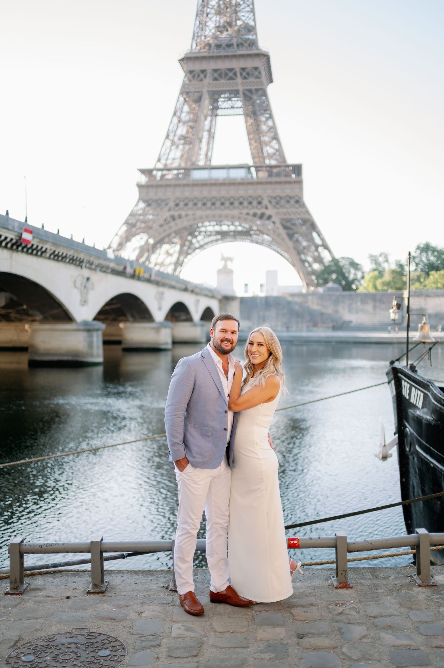Couple posing romantically in front of the Eiffel Tower and Seine River in Paris, France.