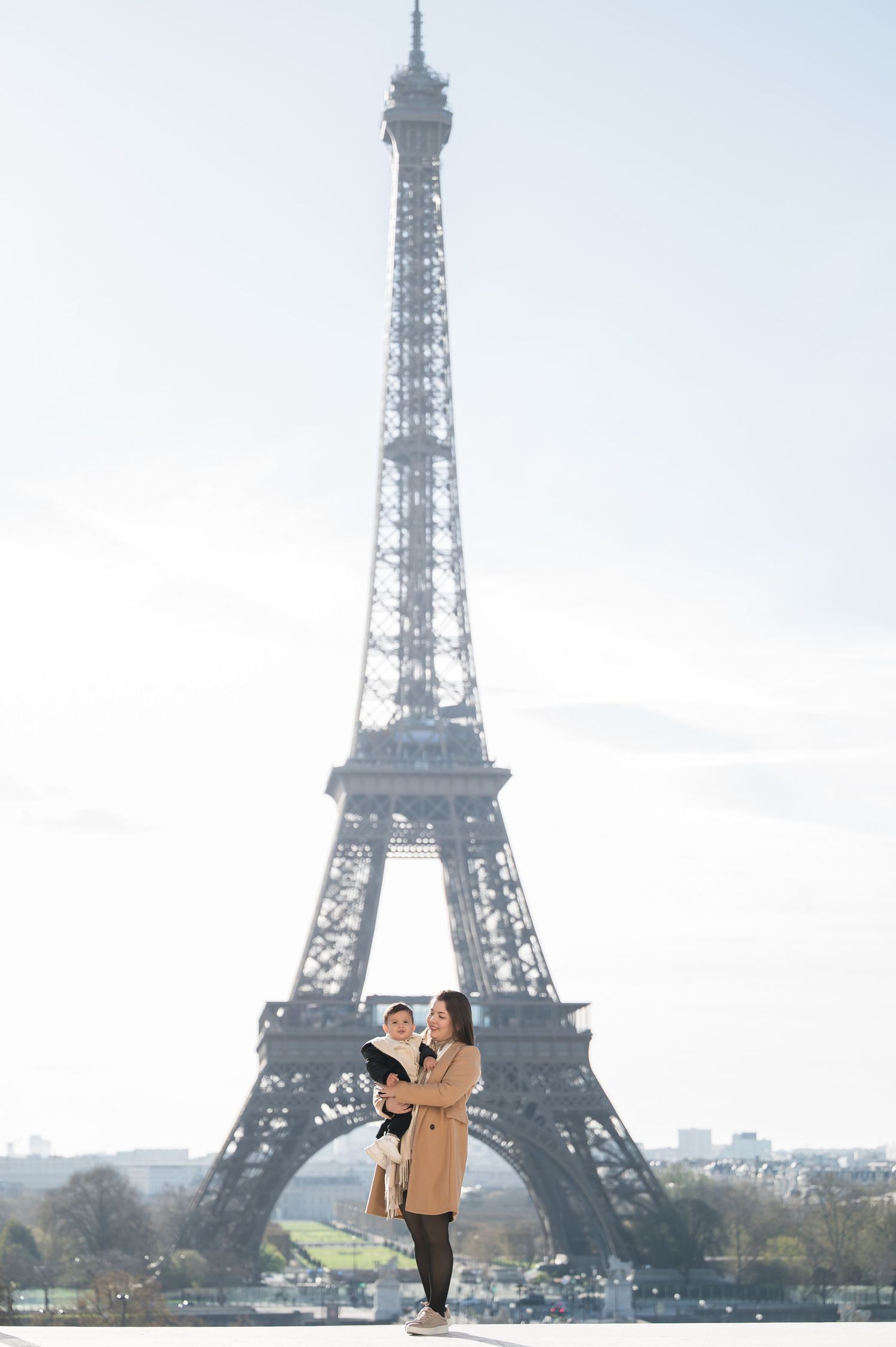 Mother holding her child in front of the Eiffel Tower in Paris.