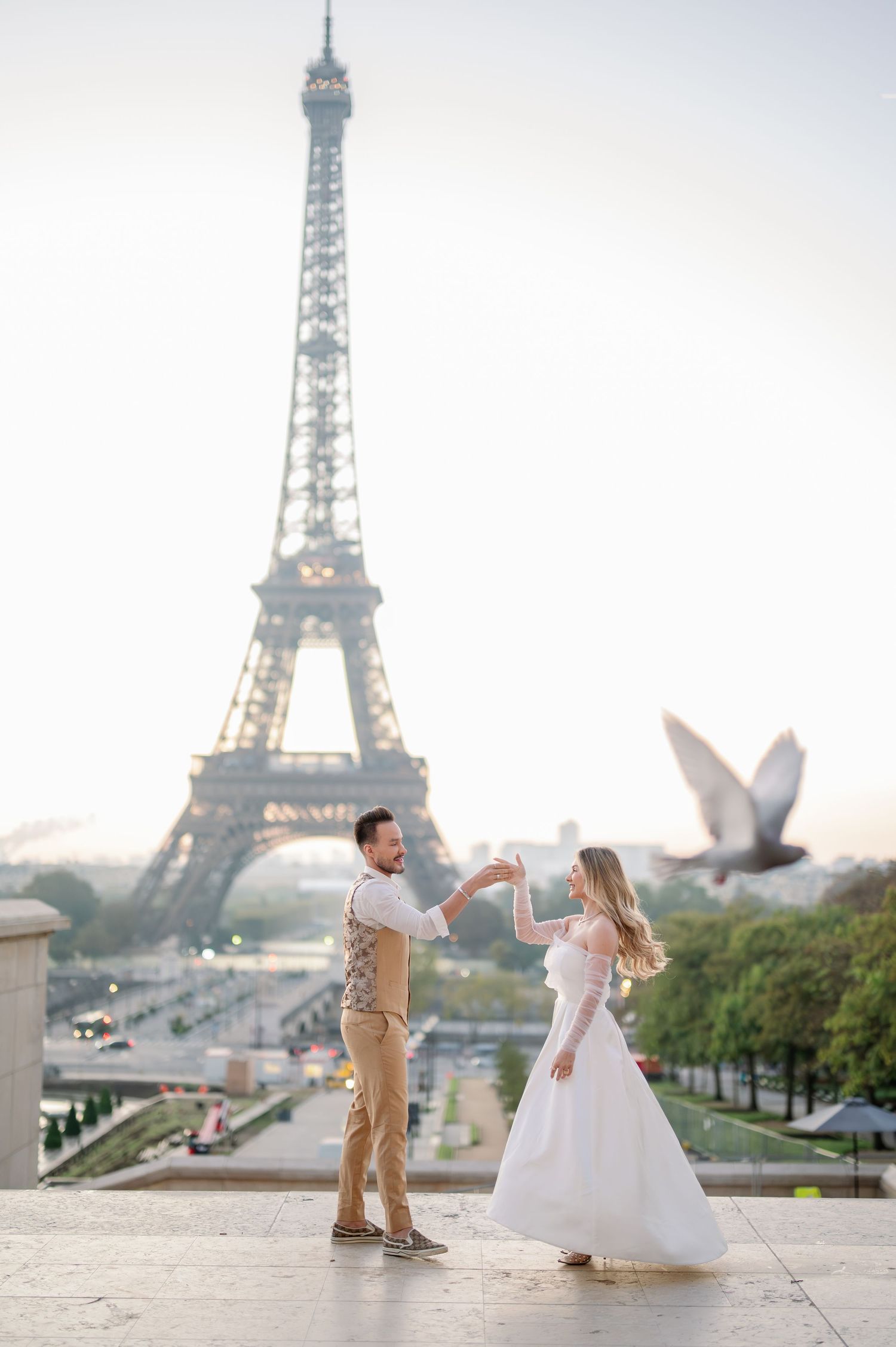 A romantic couple dancing together at sunset with the iconic Eiffel Tower in the background in Paris.