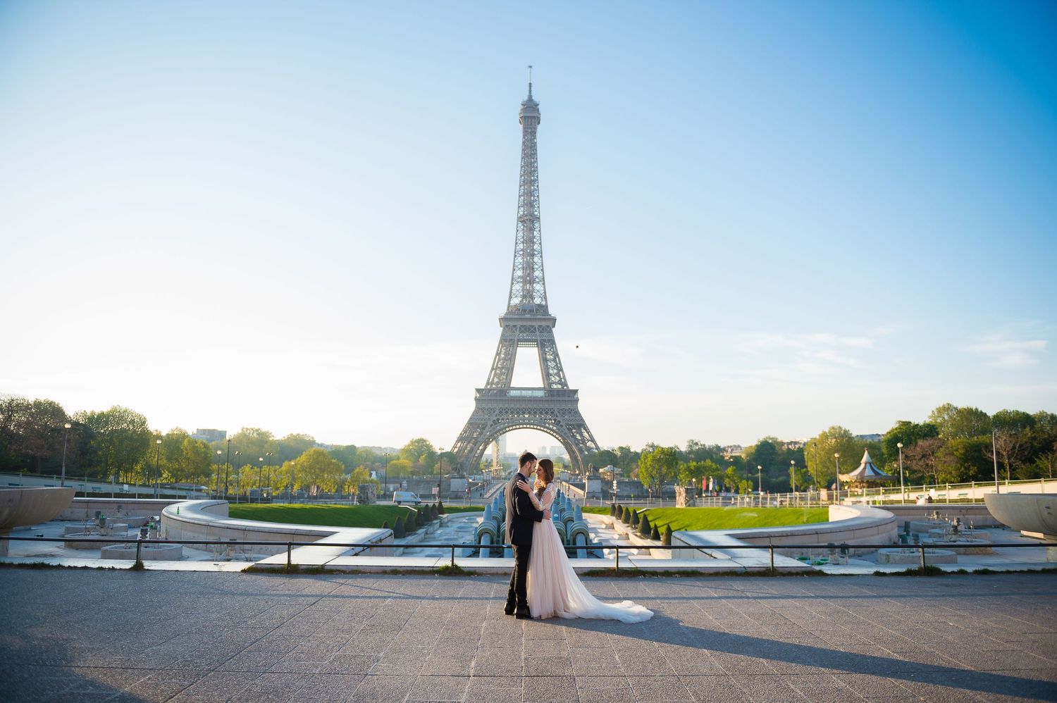 Wedding couple embracing at Trocadero plaza with Eiffel Tower in background.