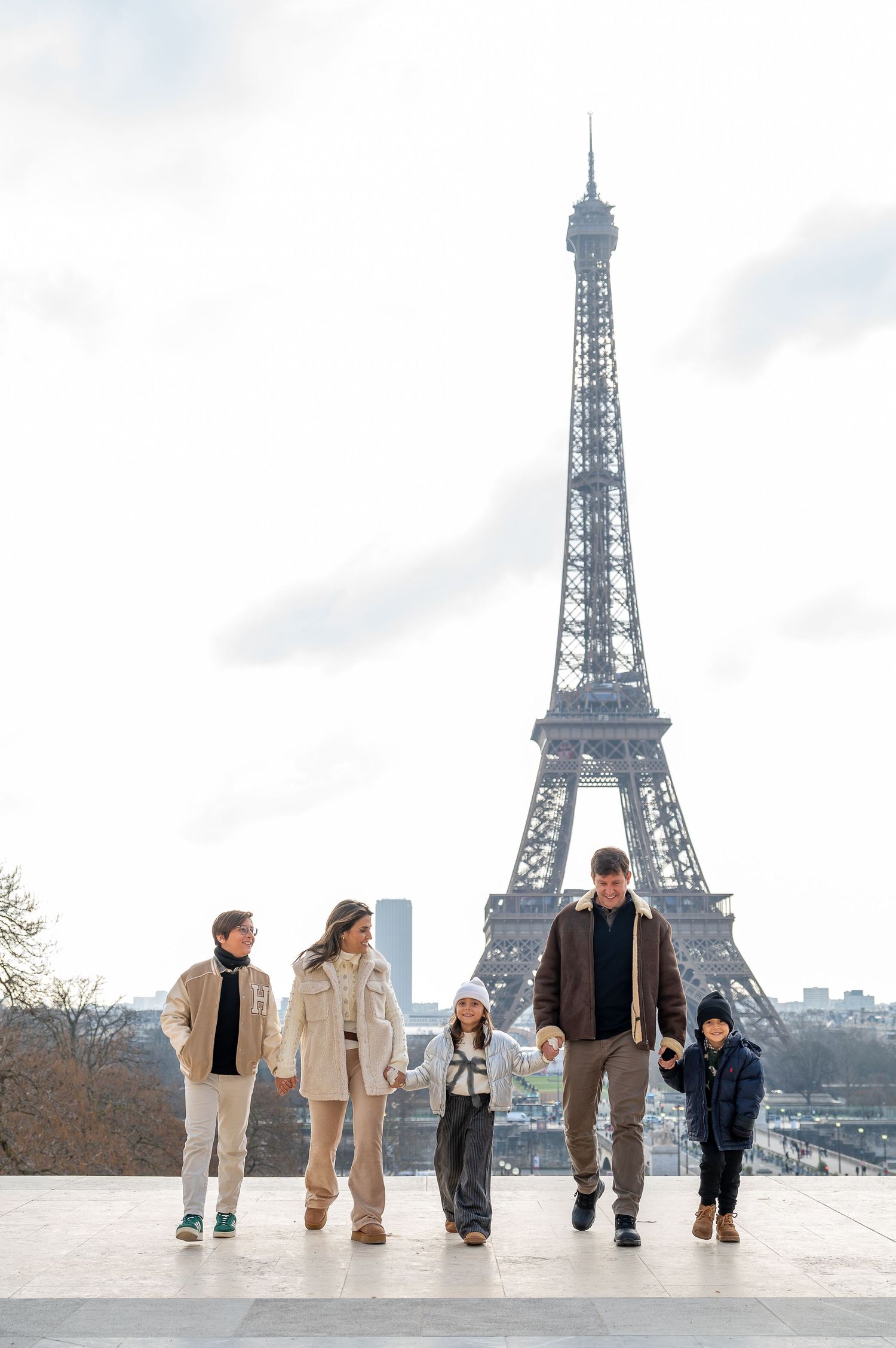 A group of tourists poses on a viewing platform with the Eiffel Tower rising behind them in Paris.