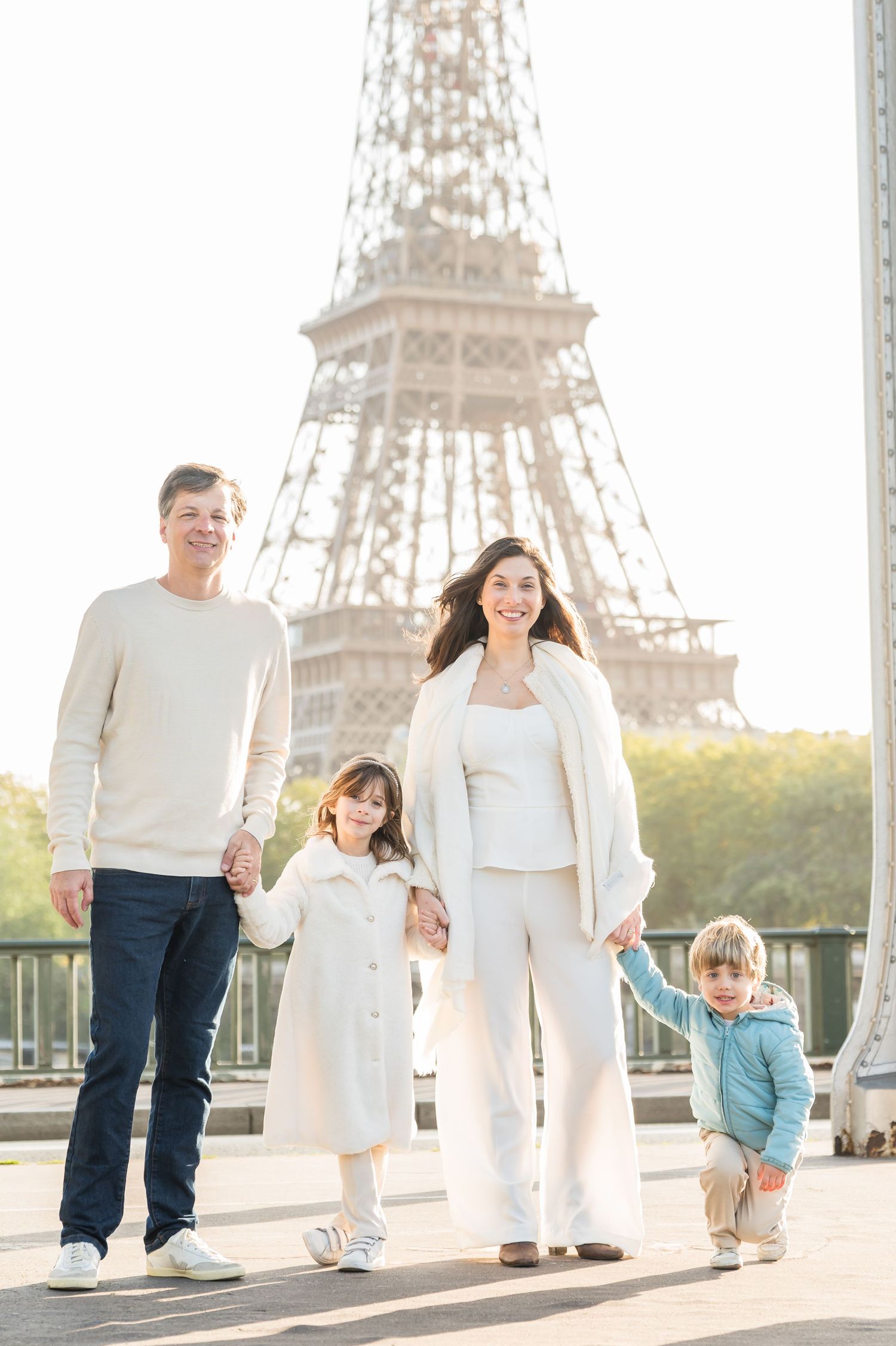 A group in coordinated white outfits strolls along a pathway with the Eiffel Tower as their backdrop.