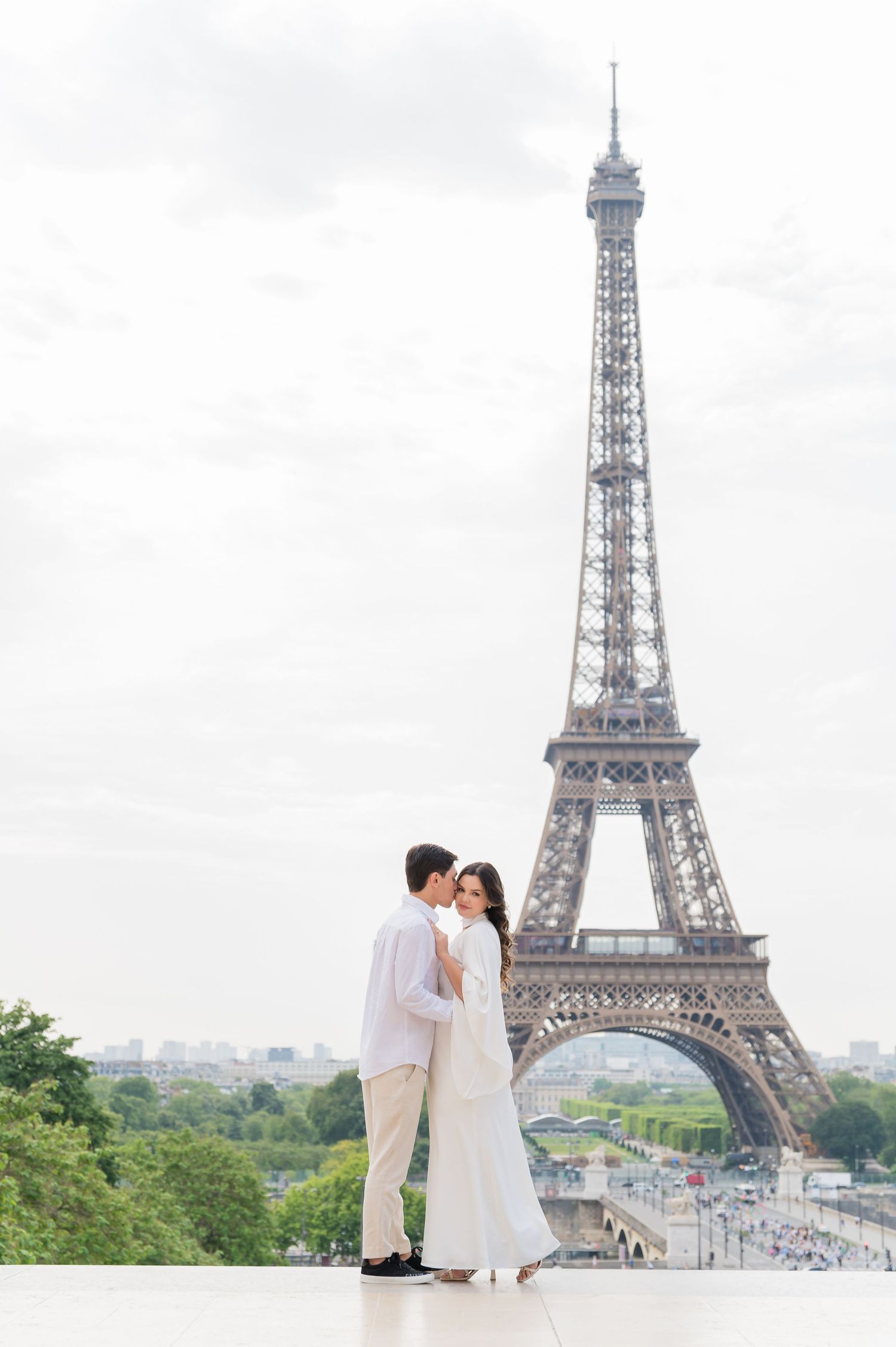 Romantic couple poses in front of the iconic Eiffel Tower in Paris during a dreamy destination photoshoot.