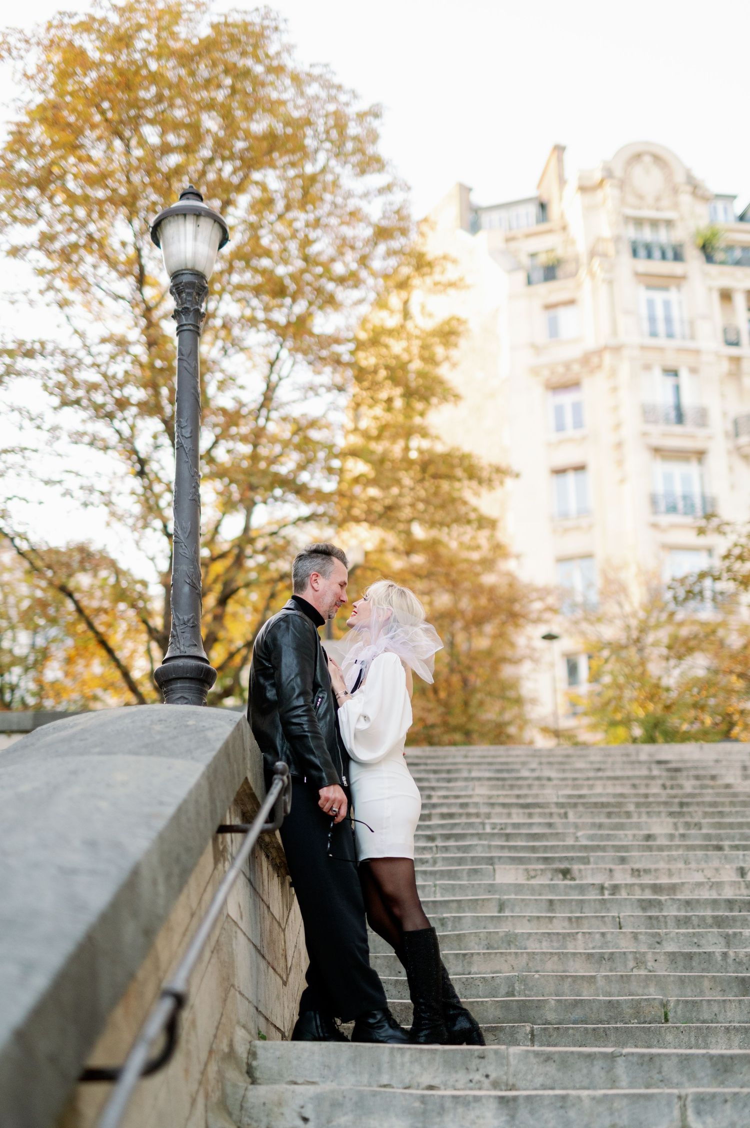 A couple shares an intimate moment on historic Paris steps during golden hour.