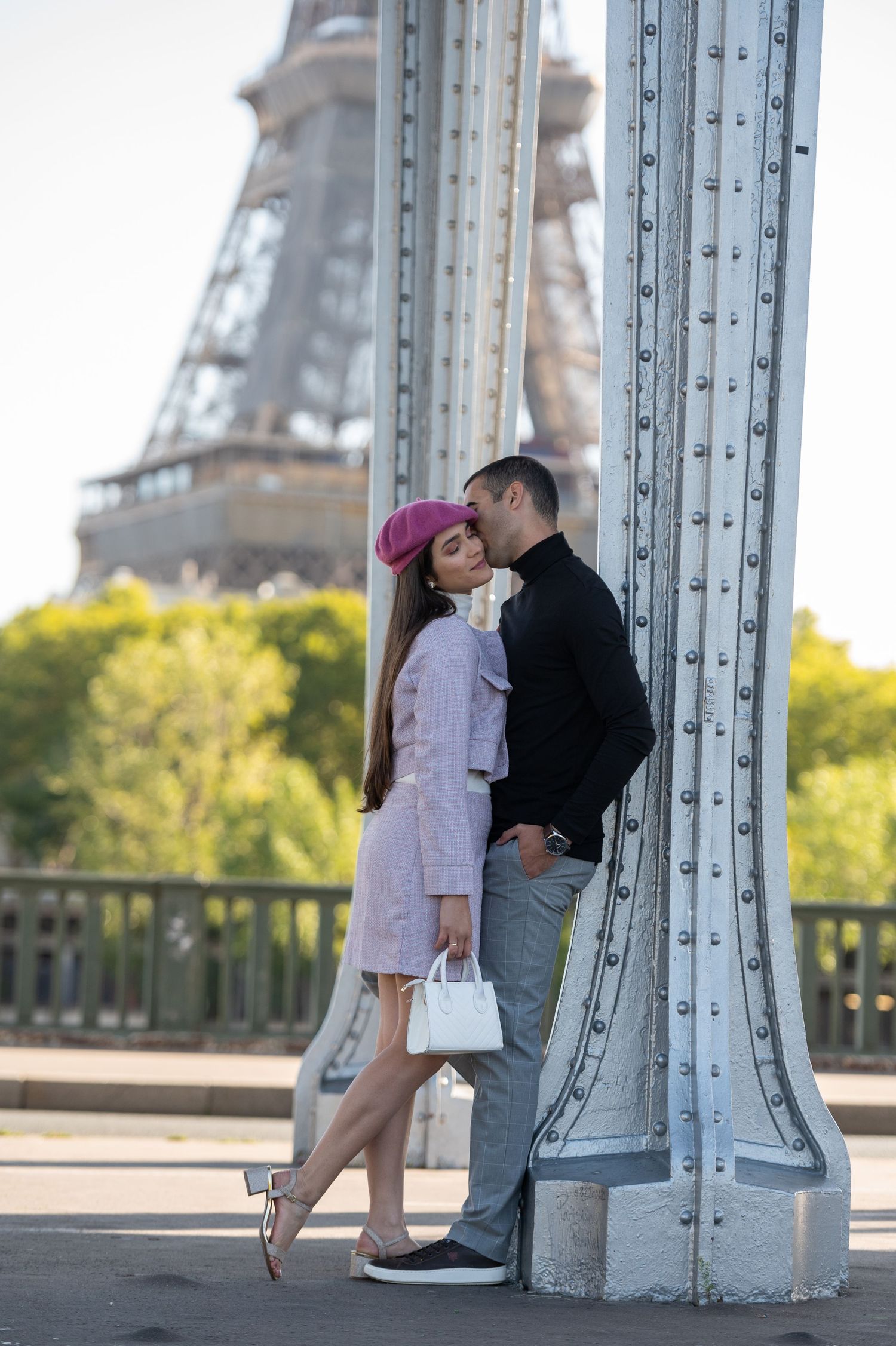 A romantic moment on a bridge near the Eiffel Tower in Paris with yellow flowers blooming in the background.