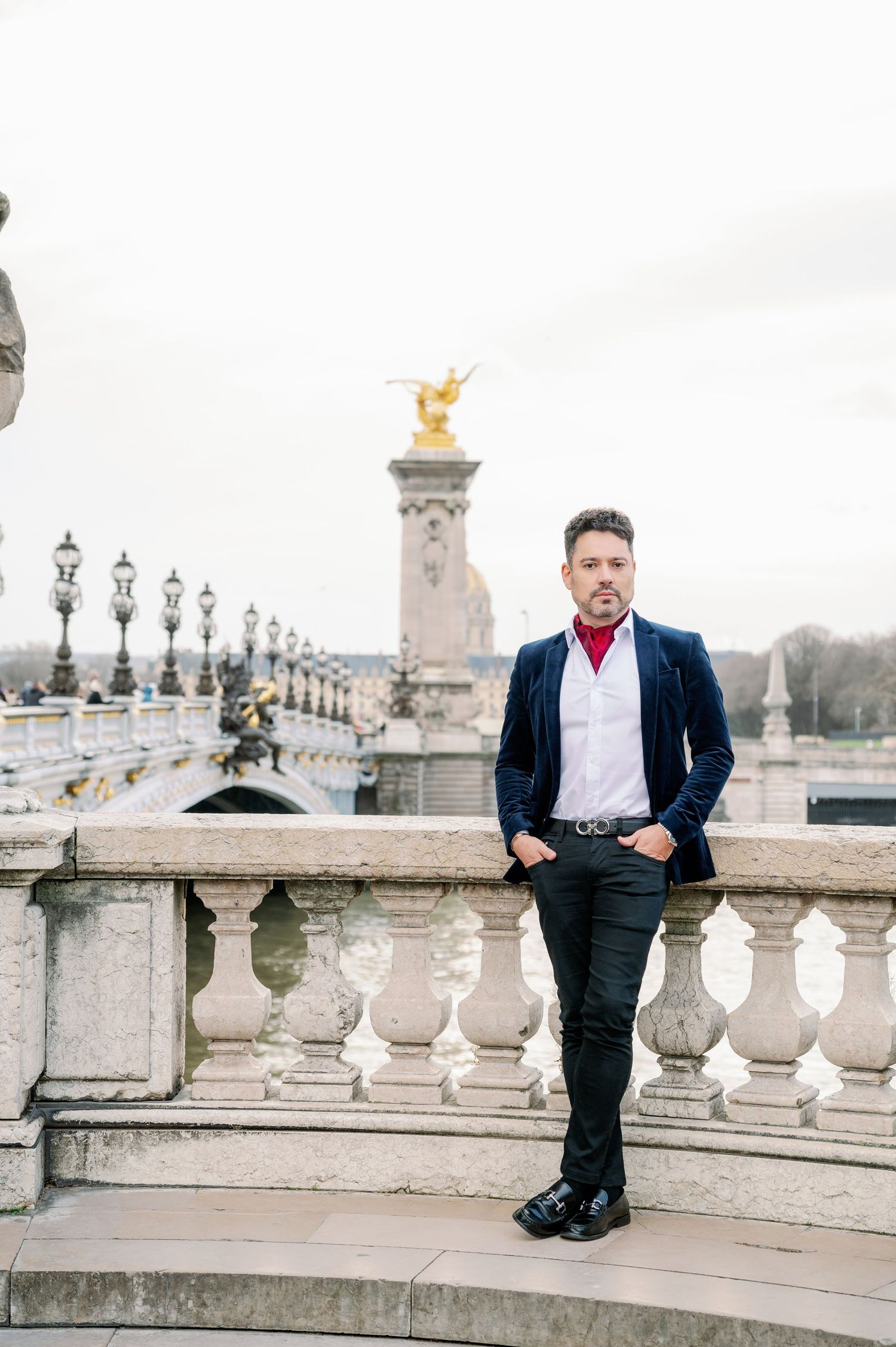 Elegant fashion photography on the iconic Pont Alexandre III bridge in Paris featuring a well-dressed figure and golden statues.