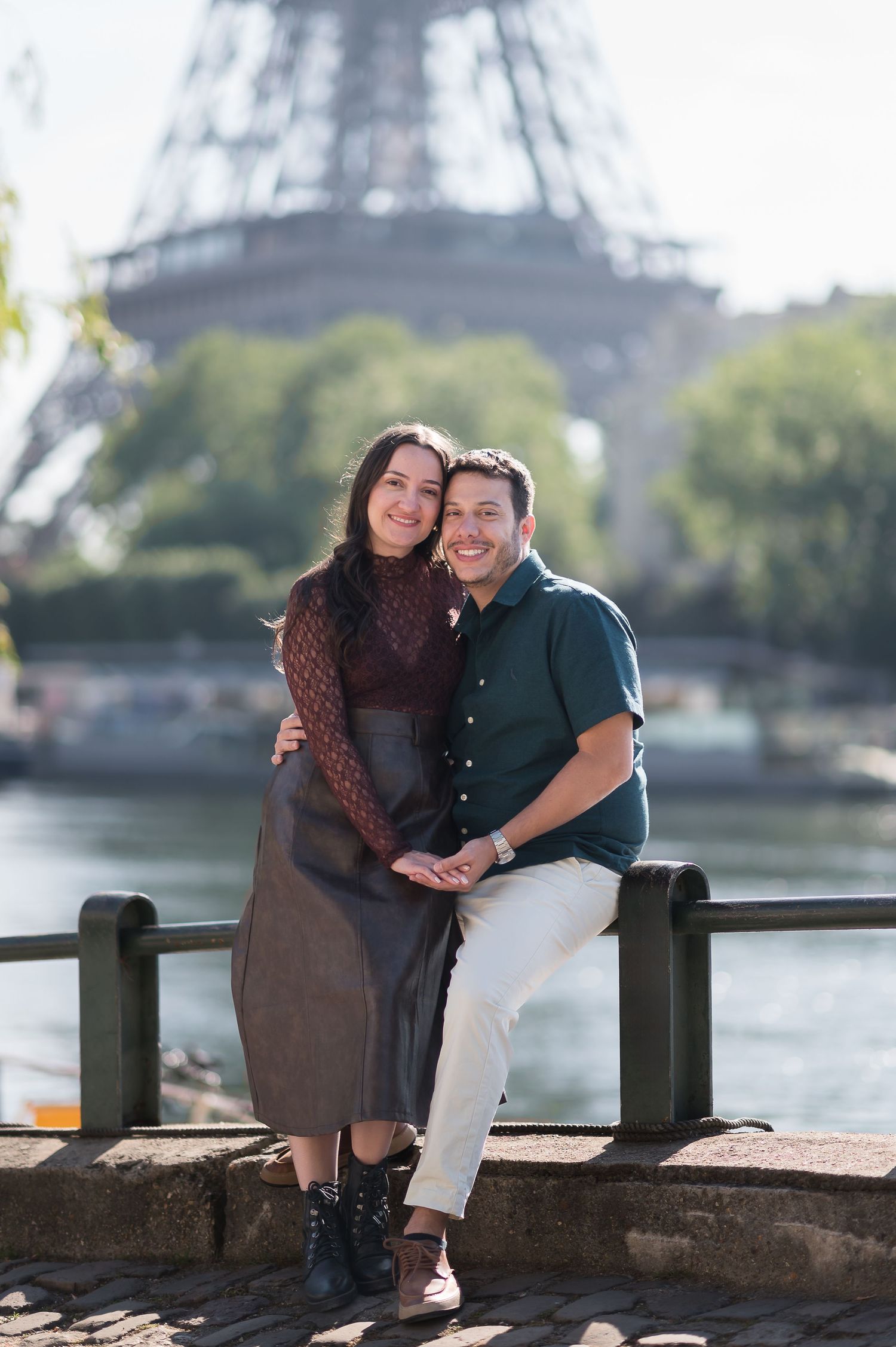 Couple smiling together in front of the Eiffel Tower by the Seine River in Paris, France.