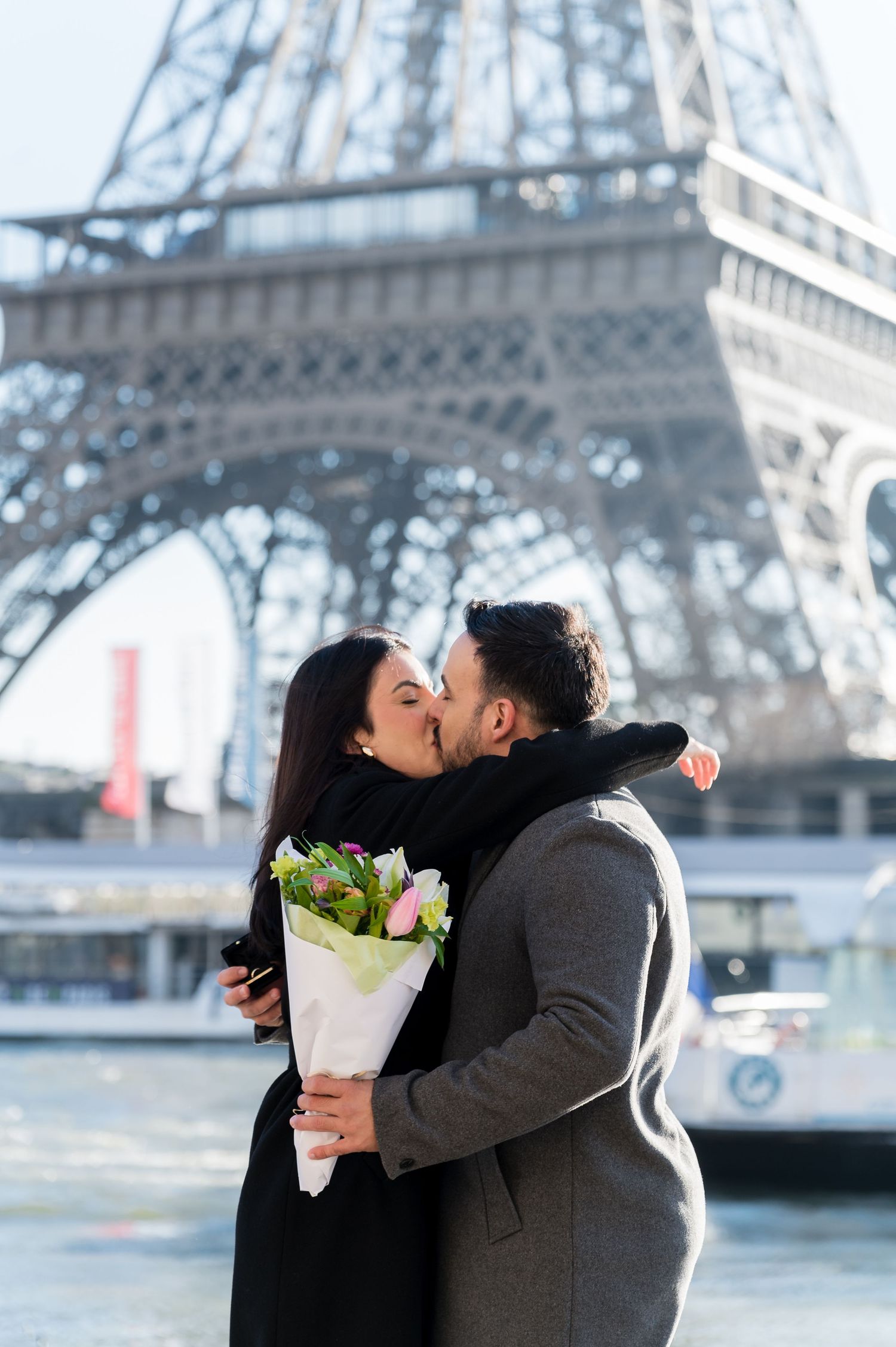 A couple shares a romantic moment with flowers in front of the Eiffel Tower in Paris.