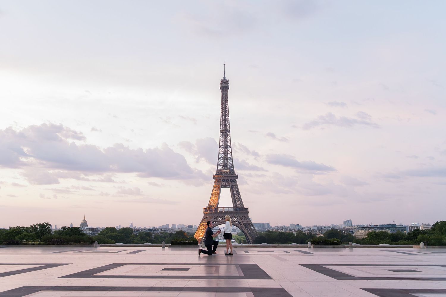 View of the iconic Eiffel Tower from the Trocadero Platform in Paris during sunset with dramatic cloudy skies.