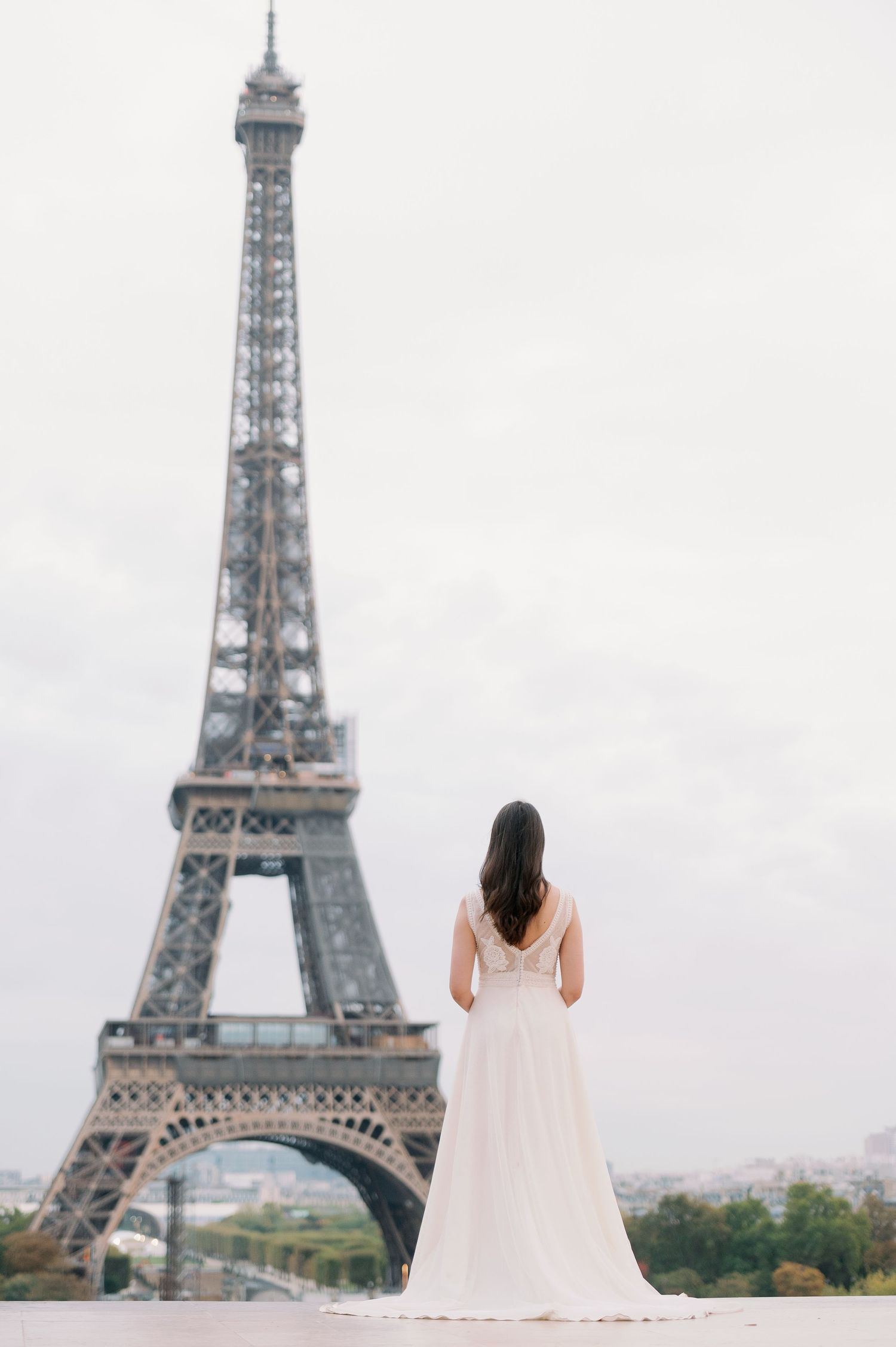 A bride in a white gown is photographed in front of the Eiffel Tower in Paris with three similar poses.