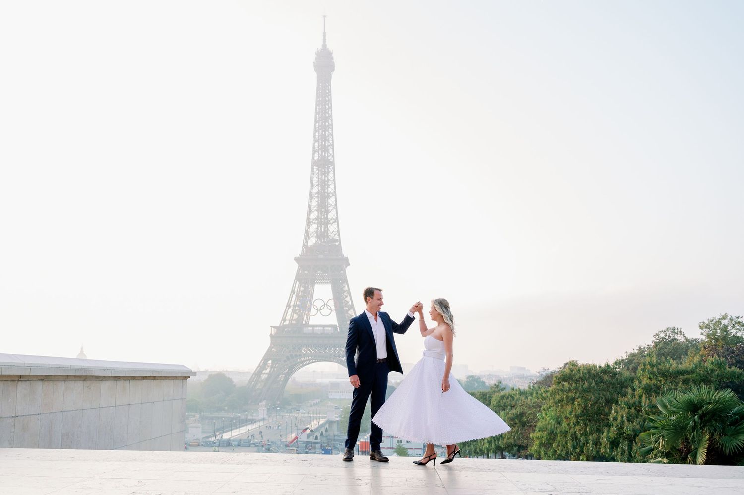 Two lovers dance together at Trocadero plaza with the iconic Eiffel Tower visible in the background in Paris, France.